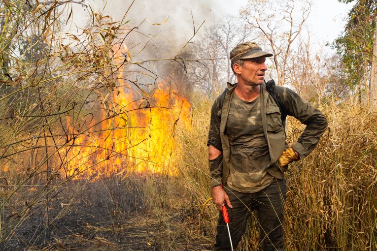 Ben Davis, an independent American conservationist, takes a break from battling a fire in the Phnom Tnout Wildlife Sanctuary, where he lives with his family in northern Cambodia. Fires in the area are lit by farmers, loggers, and local people looking to either capture wildlife or clear land for agriculture. In 2018, fires burnt in record numbers throughout the forests of north and central Cambodia. At their peak during the dry season between January and March, it is estimated up to 1,800 fires were burning in the country, more than in any other country throughout Southeast Asia at that time. Image by Sean Gallagher. Cambodia, 2020. Ben Davis, an independent American conservationist, takes a break from battling a fire in the Phnom Tnout Wildlife Sanctuary, where he lives with his family in northern Cambodia. Fires in the area are lit by farmers, loggers, and local people looking to either capture wildlife or clear land for agriculture. In 2018, fires burnt in record numbers throughout the forests of north and central Cambodia. At their peak during the dry season between January and March, it is estimated up to 1,800 fires were burning…