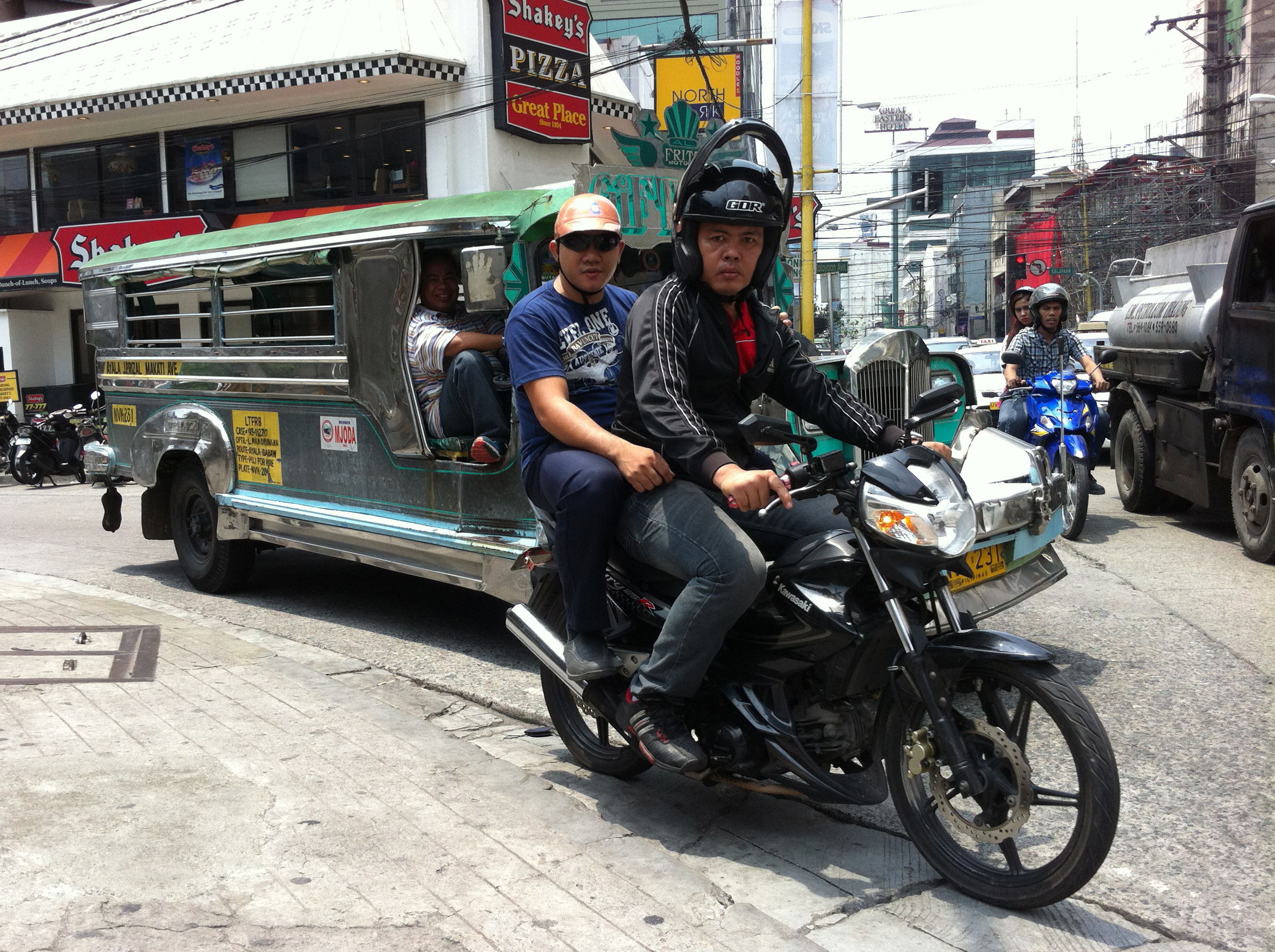 A small motorcycle and a "jeepney" minibus—the twin terrors of Manila roads. Image by Tom Hundley. Philippines, 2013. Media file: img_0182.jpg