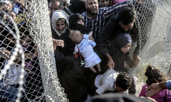 Syrian refugees rushing through a hole in the fence near the Turkish border, June 14, 2015. Image by Bulent Kilic/AFP/Getty Images. Syria, 2015.