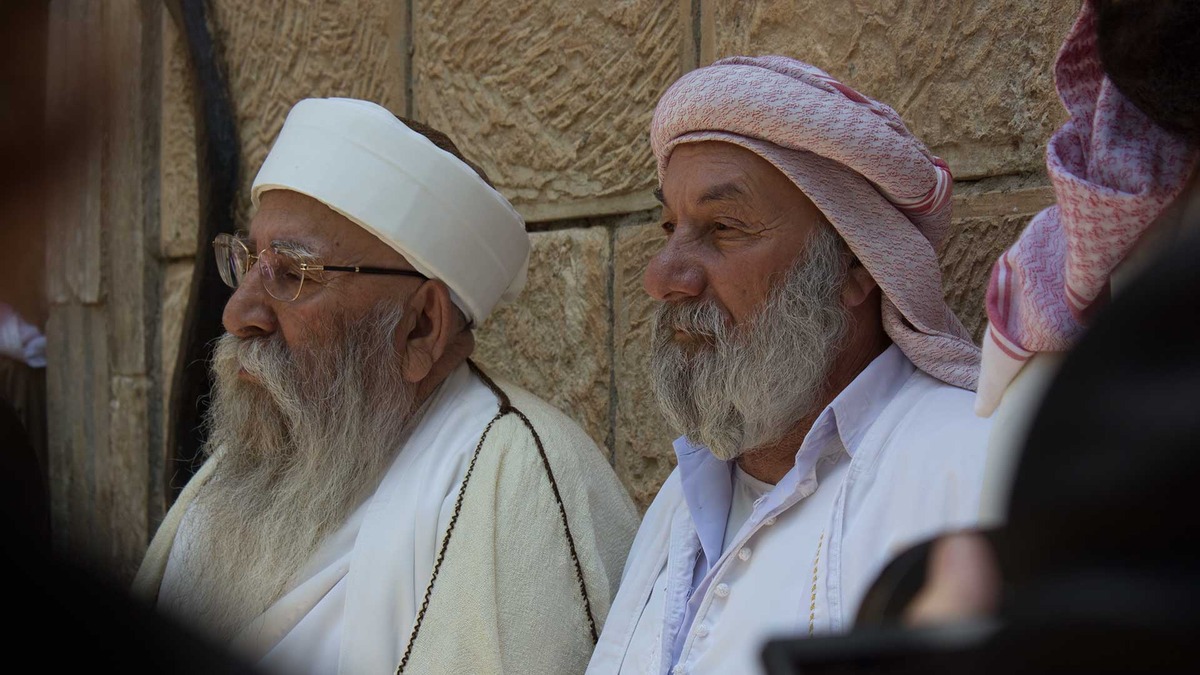 The Yazidis' top spiritual leader, Baba Sheikh (left), tells a group of ISIS survivors that he will pray for them as they head to Europe for trauma treatment. Image by Emily Feldman. Iraq, 2015.