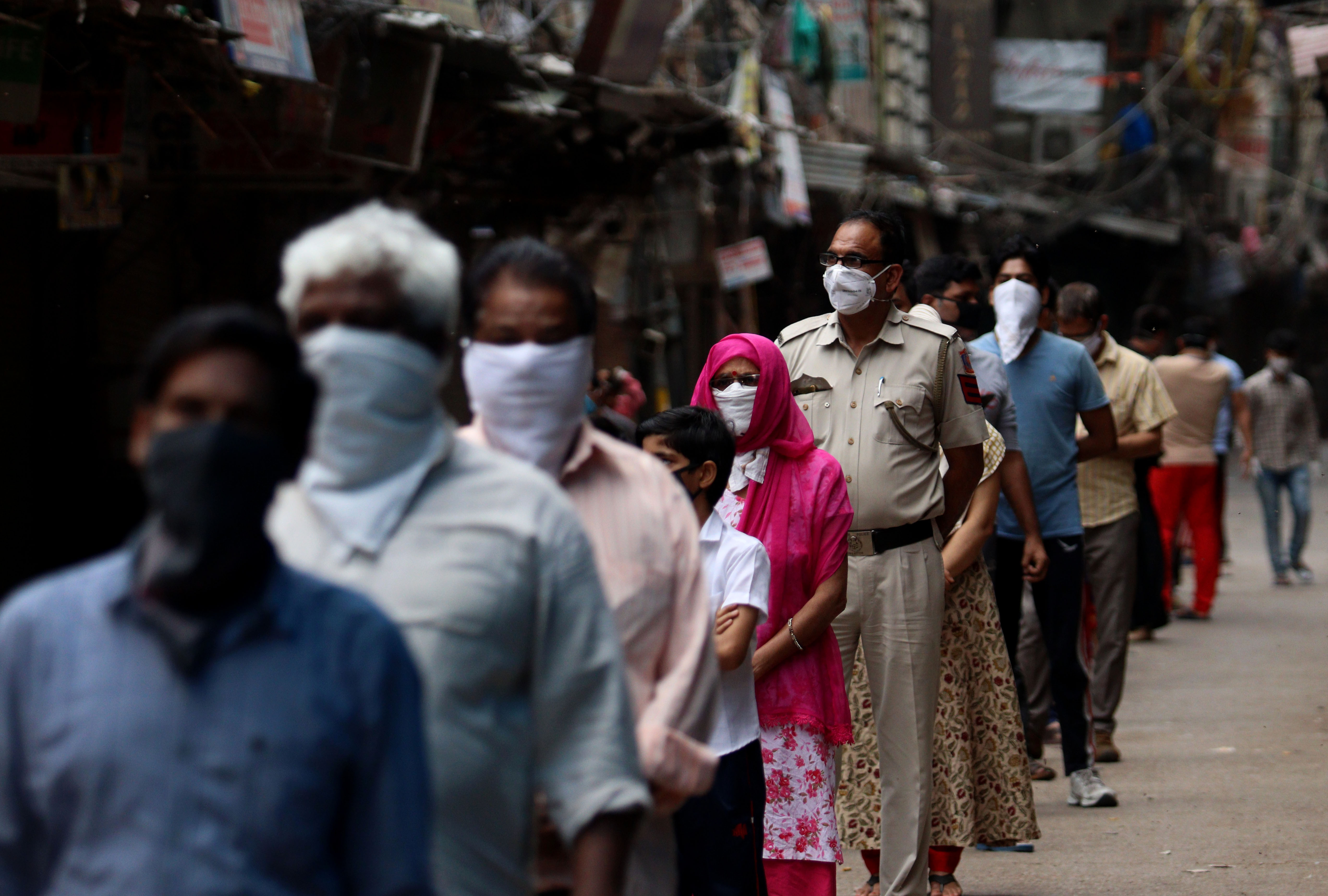 Mobile Covid-19 testing van in India. Delhi Police cop along with people stands in a queue for coronavirus test at Red Zone area, old Delhi. Image by Exposure Visuals / Shutterstock. India, 2020. Mobile Covid-19 testing van in India. Delhi Police cop along with people stands in a queue for coronavirus test at Red Zone area, old Delhi. Image by Exposure Visuals / Shutterstock. India, 2020.