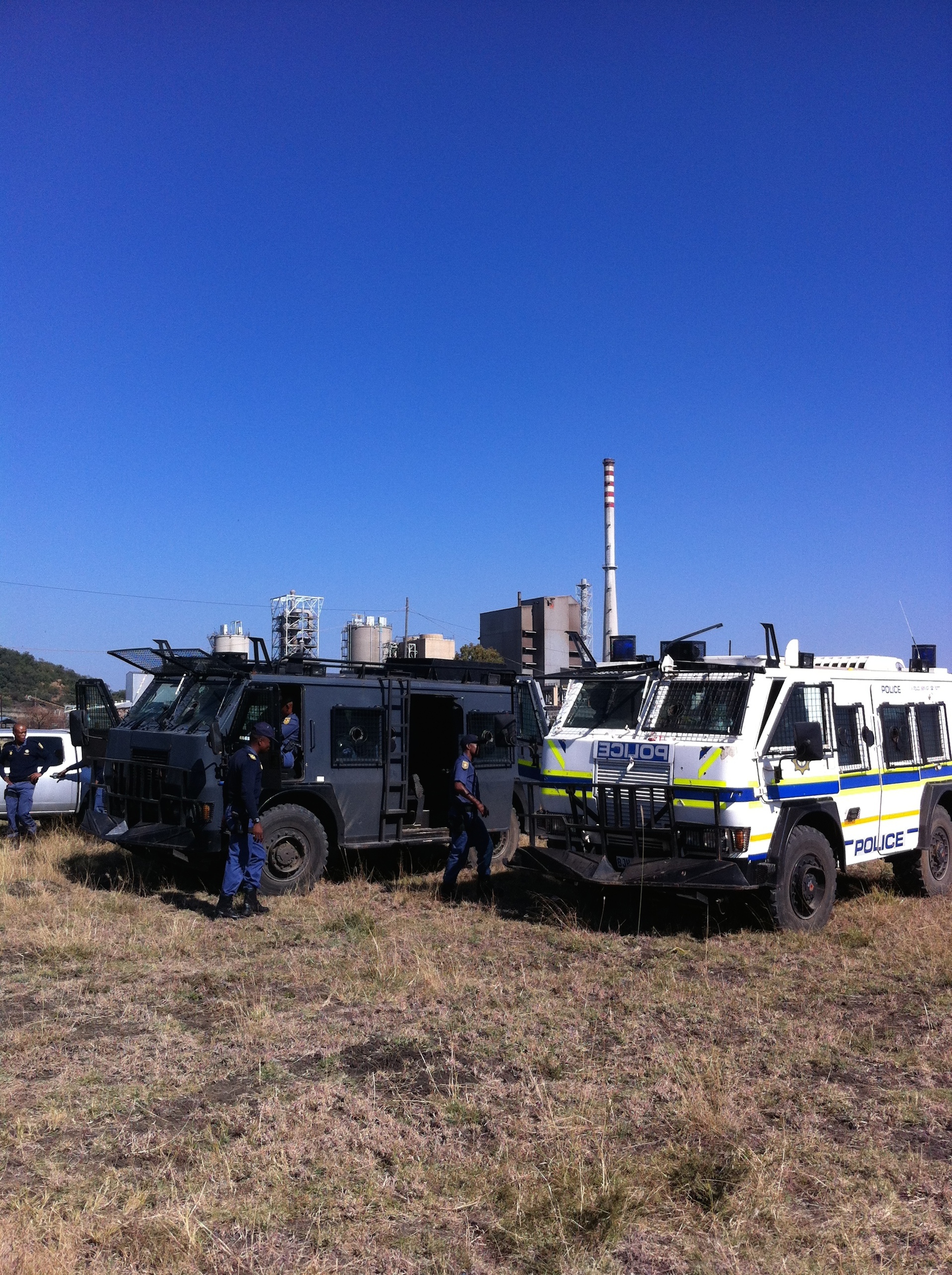 Police 'hippos' take up positions in the scrubland between Nkaneng settlement and the Lonmin mine, as South Africa's longest strike action comes to a head. Image by Jason Larkin. South Africa, 2014.