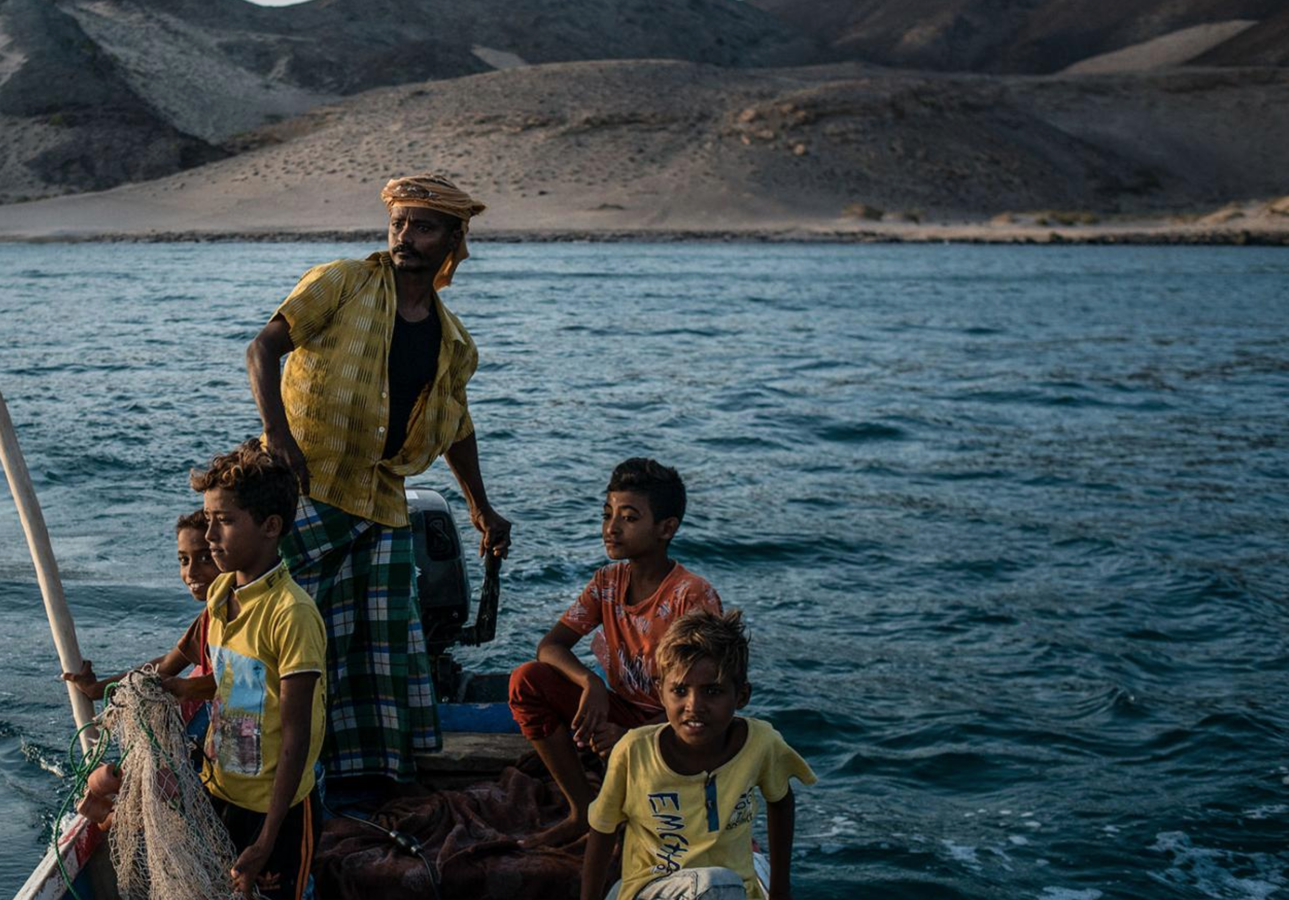 Shafai Saleh Hadi drives a friend's boat along the coast of Bir Fuqum, searching for fish with his sons. Image by Alex Potter. Yemen, 2018. Shafai Saleh Hadi drives a friend's boat along the coast of Bir Fuqum, searching for fish with his sons. Image by Alex Potter. Yemen, 2018.
