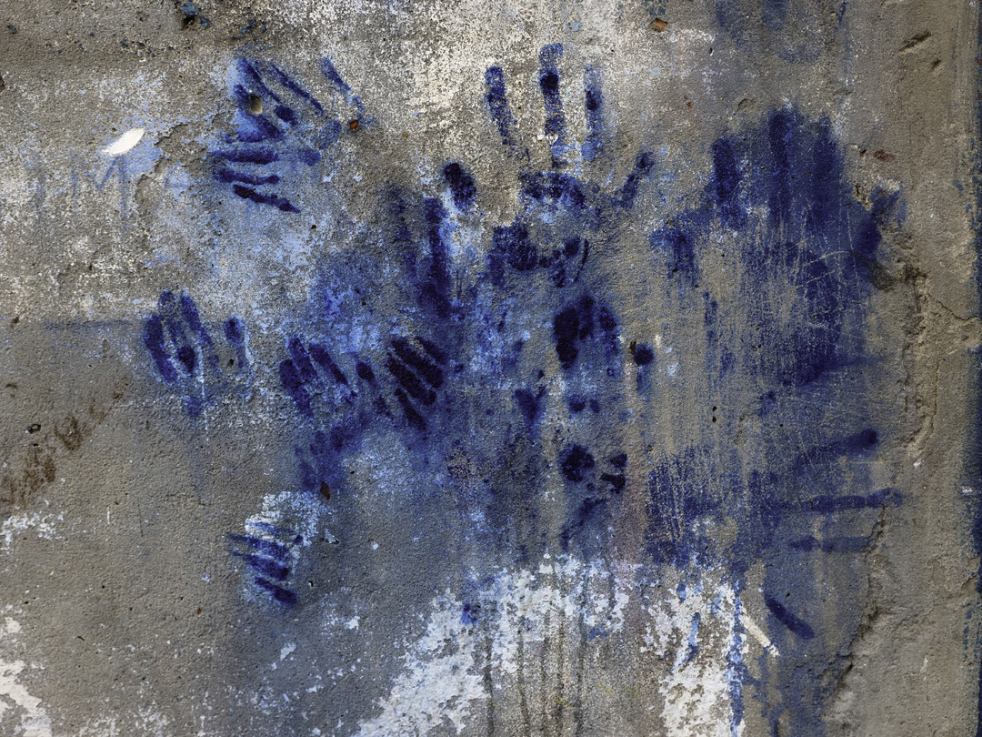 Handprints in chromium sulfate accumulate on the outside of a tannery wall. Workers pat the walls during breaks to wipe chemicals from their hands.