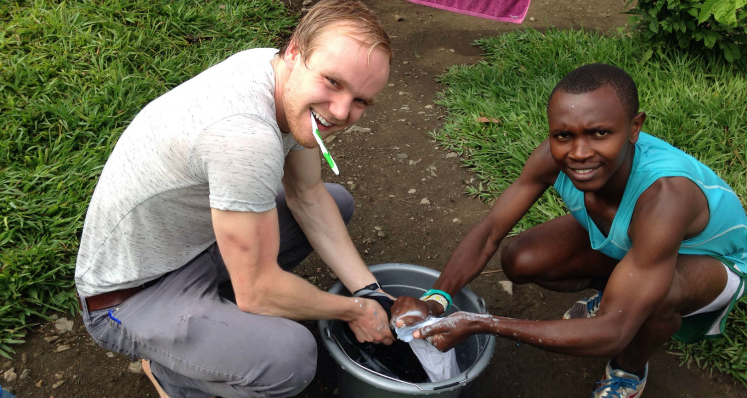 Graduate student Daniel Socha works with a member of the Project Kirotshe running team on how to wash his running clothes. Democratic Republic of Congo, 2016. Image courtesy of Daniel Socha and Kent State University.
