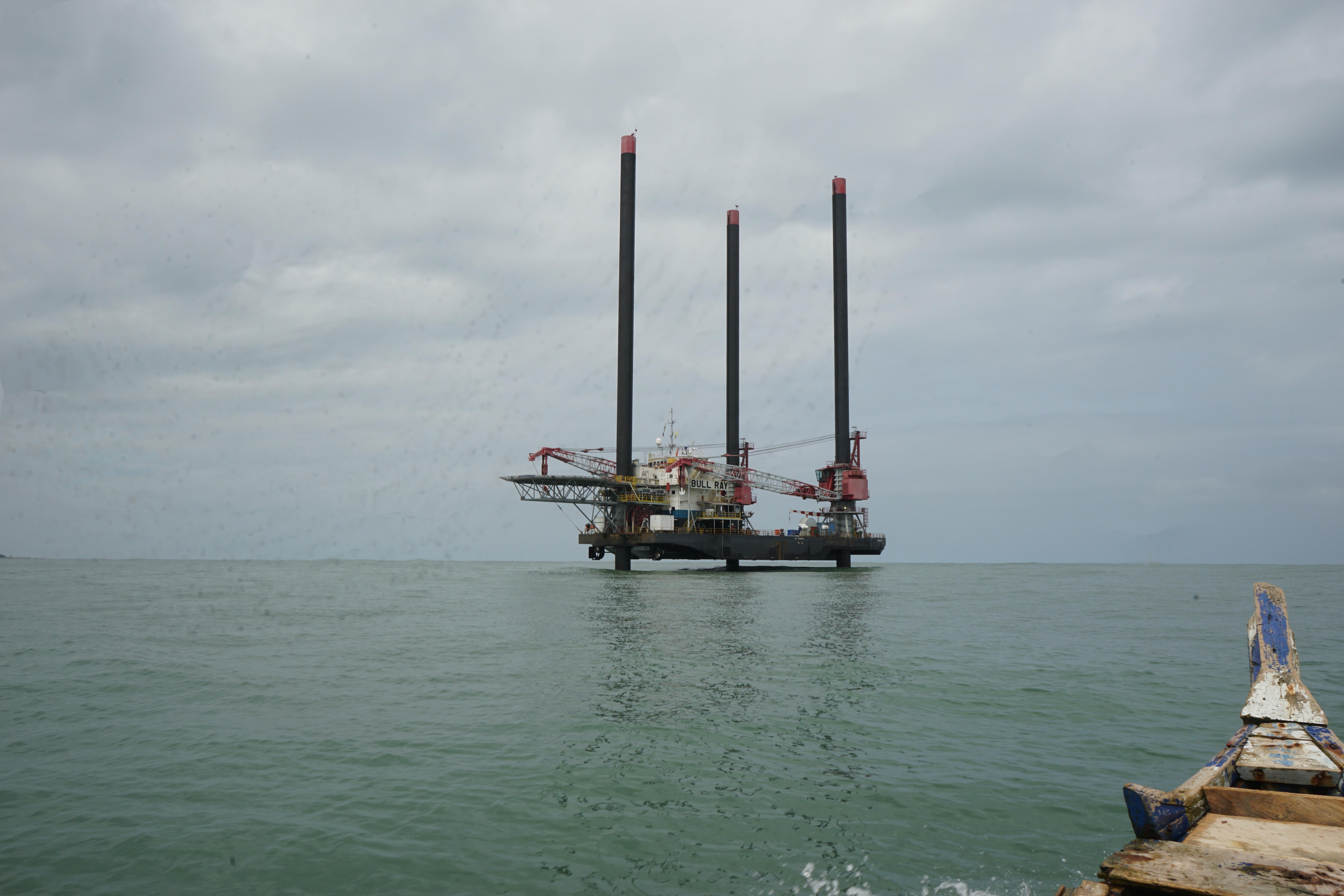 Oil production vessels like this now dot the west coast of Ghana. Employees will usually work for a few weeks on the vessel and then for a few weeks on the mainland. This photo was captured from a traditional fishing canoe, the main method of navigating the ocean for most of Ghana's fishermen. Image by John Soper. Ghana, 2015.