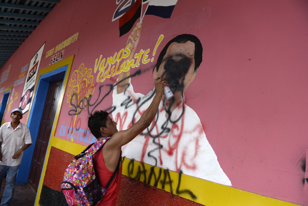 A peasant scrawls on a mural of Nicaraguan President Daniel Ortega during a protest against the construction of an inter-oceanic canal in Juigalpa, Nicaragua. Nicaragua and Chinese company HKND Group last year launched construction of an ambitious $50 billion rival to the Panama canal that could handle even larger ships. The canal, which is set to be completed within five years, threatens to displace a small village of the Rama ethnic group and to invade the Indio Maiz reserve, according to environmentalists. Image by STR/AFP/Getty Images. Nicaragua, 2015. Media file: 107515-full.jpg