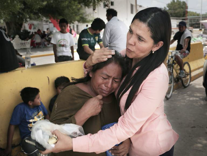 Gladys Edil Caas, a local Mexican volunteer who delivers water, blankets and other needs to migrants camped out by the bridge, consoles a Guatemalan woman during a visit to the camp. Image by Jose A Iglesias. Mexico, 2019. Gladys Edil Caas, a local Mexican volunteer who delivers water, blankets and other needs to migrants camped out by the bridge, consoles a Guatemalan woman during a visit to the camp. Image by Jose A Iglesias. Mexico, 2019.