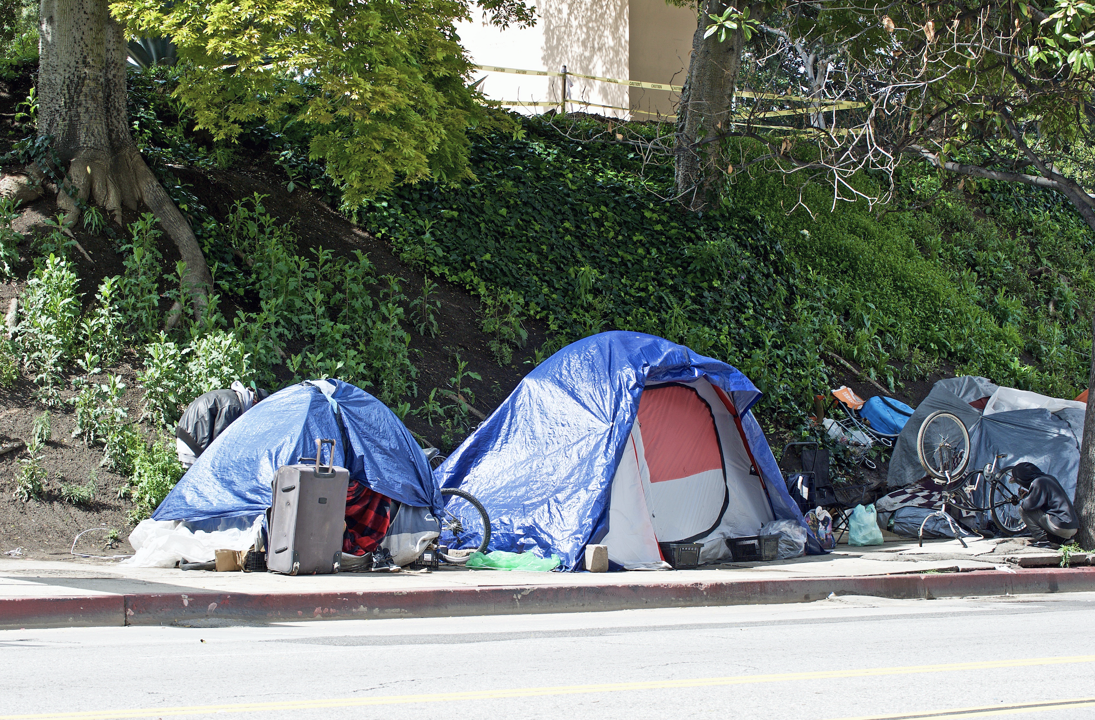 Homeless encampments along a Los Angeles roadside on April 8, depicting the growing epidemic of homelessness amid the worldwide COVID-19 pandemic. Image by Philip Pilosian/Shutterstock. United States, 2020. Homeless encampments along a Los Angeles roadside on April 8, depicting the growing epidemic of homelessness amid the worldwide COVID-19 pandemic. Image by Philip Pilosian/Shutterstock. United States, 2020.