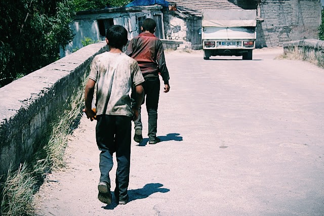 After a day's work, boys cross the iron bridge after which their village Demirkopru Koyu is named. Image by Selin Thomas. Turkey, 2014.