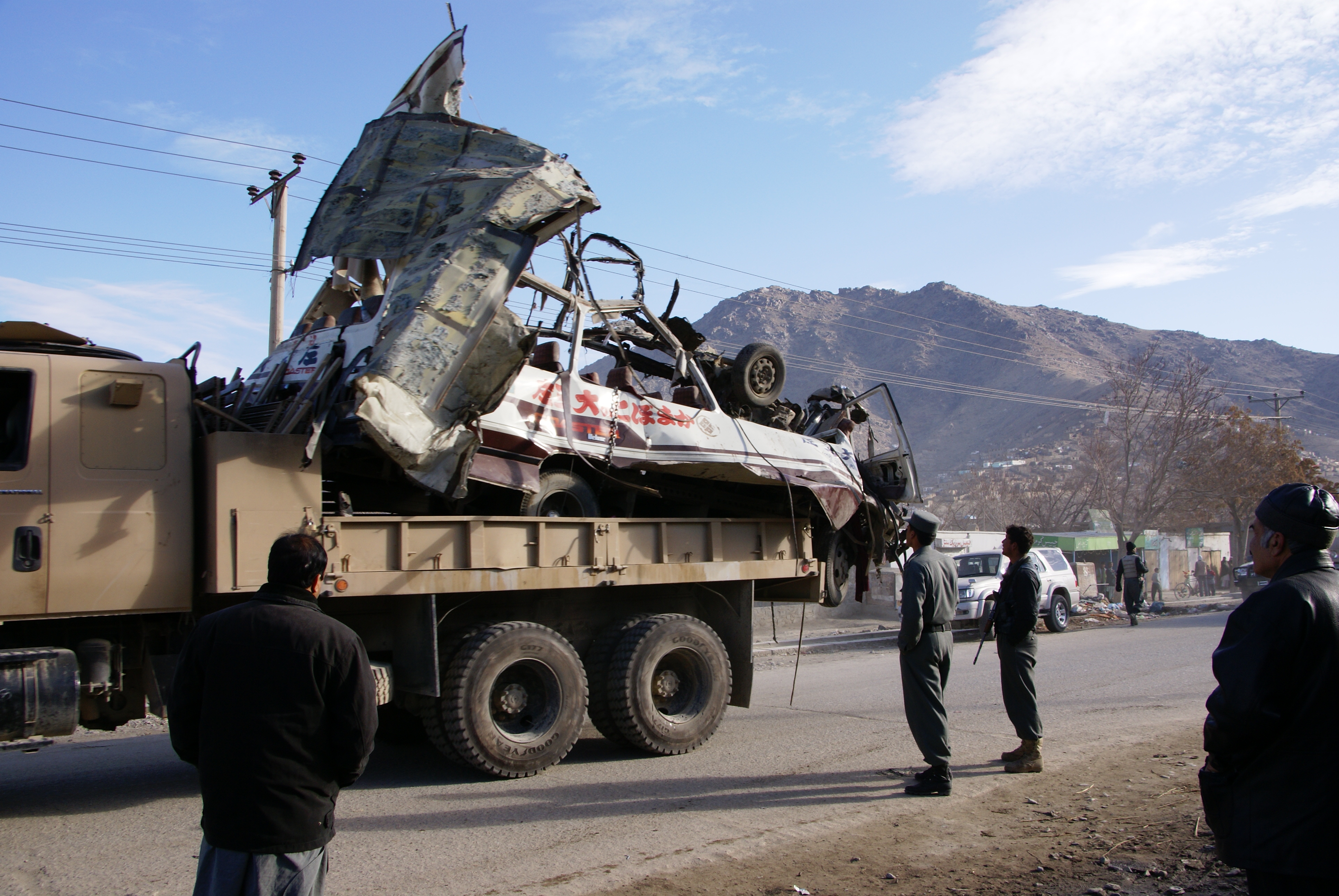 The remains of a bus are hauled away after a bombing in Kabul. Image by Jeffrey Stern. Afghanistan, 2013. Media file: dsc02697.jpg