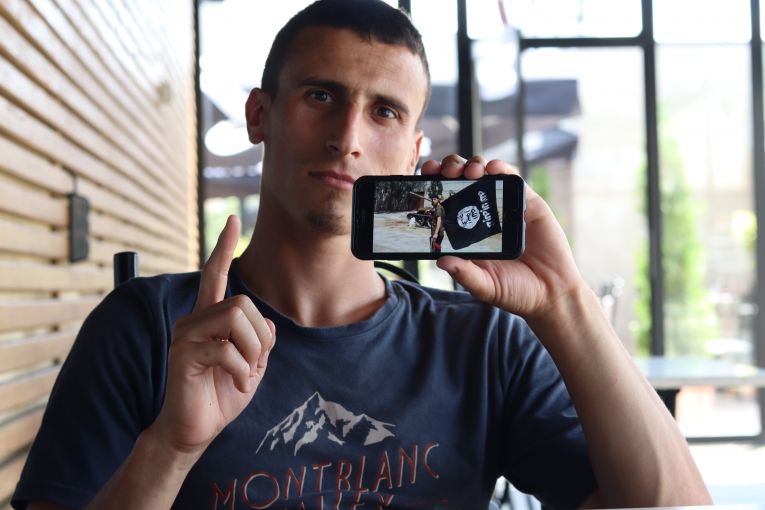 Seated at a cafe next to the dilapidated Grand Hotel in Pristina, Fitim Lladrovci, 28, is one of the only former Kosovar Islamic State fighters released from a three-year prison sentence and free to roam the streets. Image by AJ Naddaff. Kosovo, 2018. Seated at a cafe next to the dilapidated Grand Hotel in Pristina, Fitim Lladrovci, 28, is one of the only former Kosovar Islamic State fighters released from a three-year prison sentence and free to roam the streets. Image by AJ Naddaff. Kosovo, 2018.