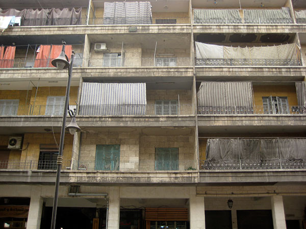 While the architects of this high-rise thought residents would enjoy the view, many Allepines create privacy by hanging tarps across their balconies. Media file: 08_Aleppo_Sheets_Covering_High_Rise.jpg