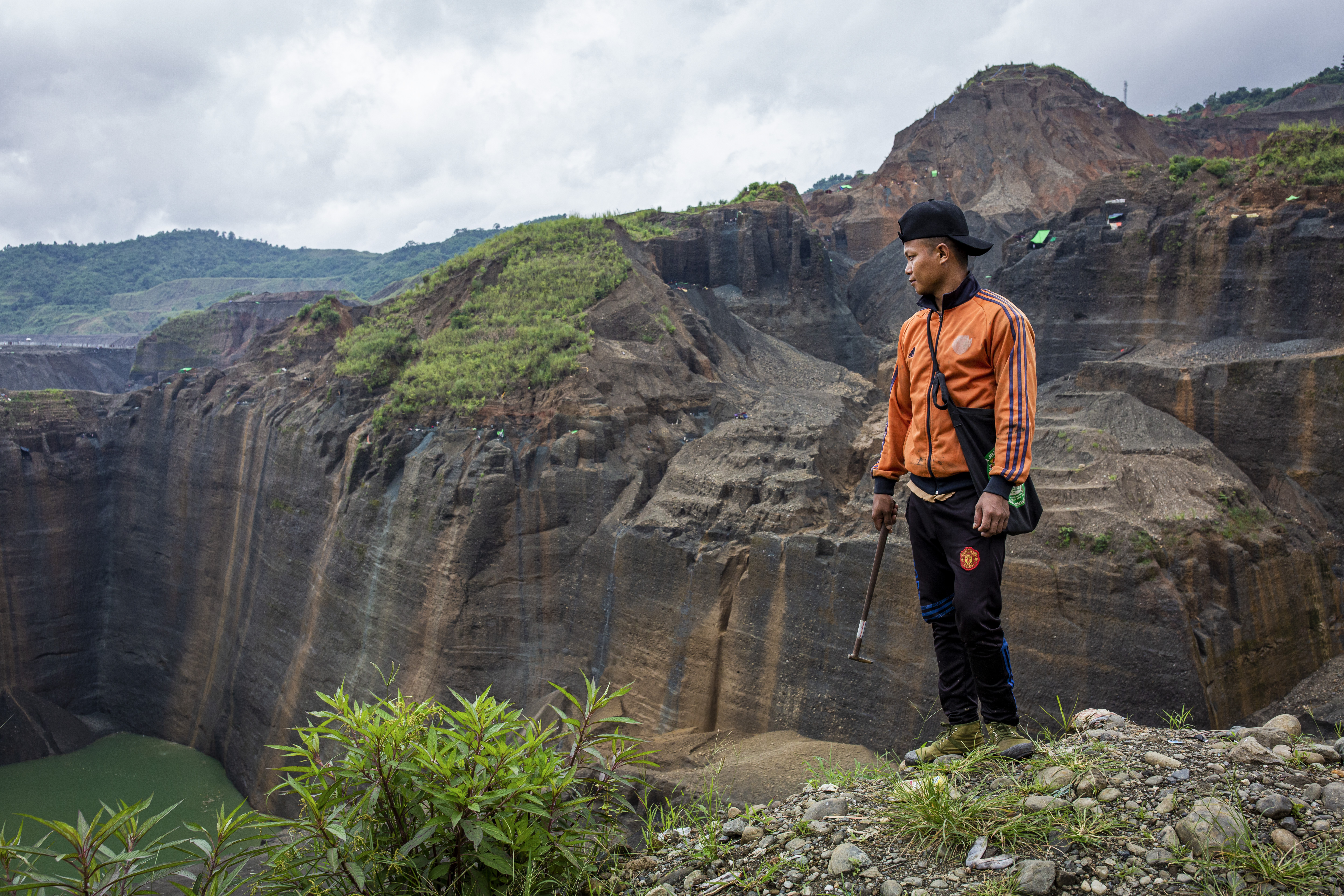 Gum Jat, 31, looks over a jade mining site in Hpakant, Kachin State, where he has worked as a freelance miner for eight years. Image by Hkun Lat/Frontier. Myanmar, 2020. Gum Jat, 31, looks over a jade mining site in Hpakant, Kachin State, where he has worked as a freelance miner for eight years. Image by Hkun Lat/Frontier. Myanmar, 2020.