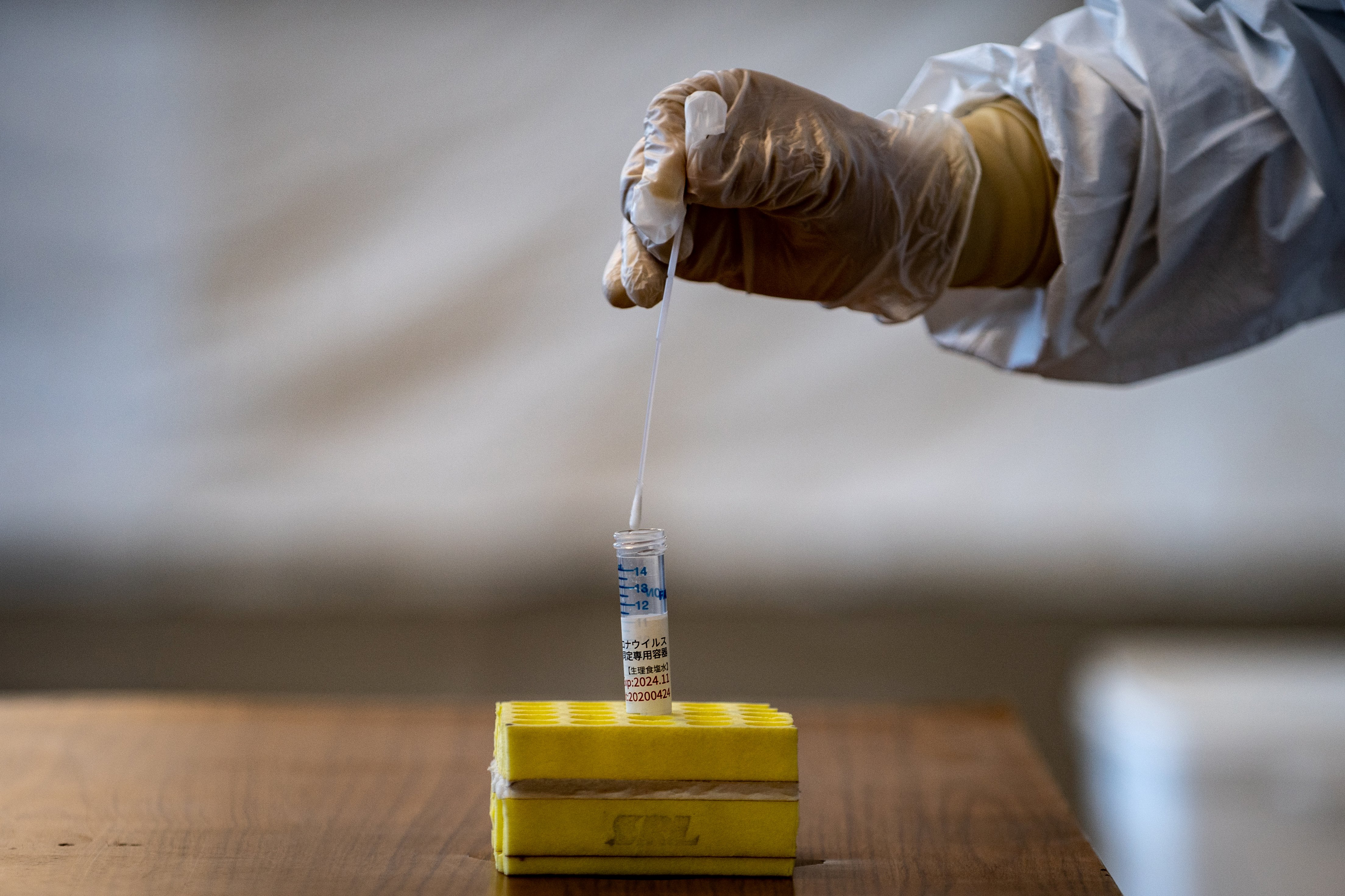 A medical staff member wearing protective clothing puts a swab into a container during demonstration of the Polymerase Chain Reaction (PCR) swab test for COVID-19 in Tokyo on May 8, 2020. Image by Philip Fong/AFP. Japan, 2020. A medical staff member wearing protective clothing puts a swab into a container during demonstration of the Polymerase Chain Reaction (PCR) swab test for COVID-19 in Tokyo on May 8, 2020. Image by Philip Fong/AFP. Japan, 2020.
