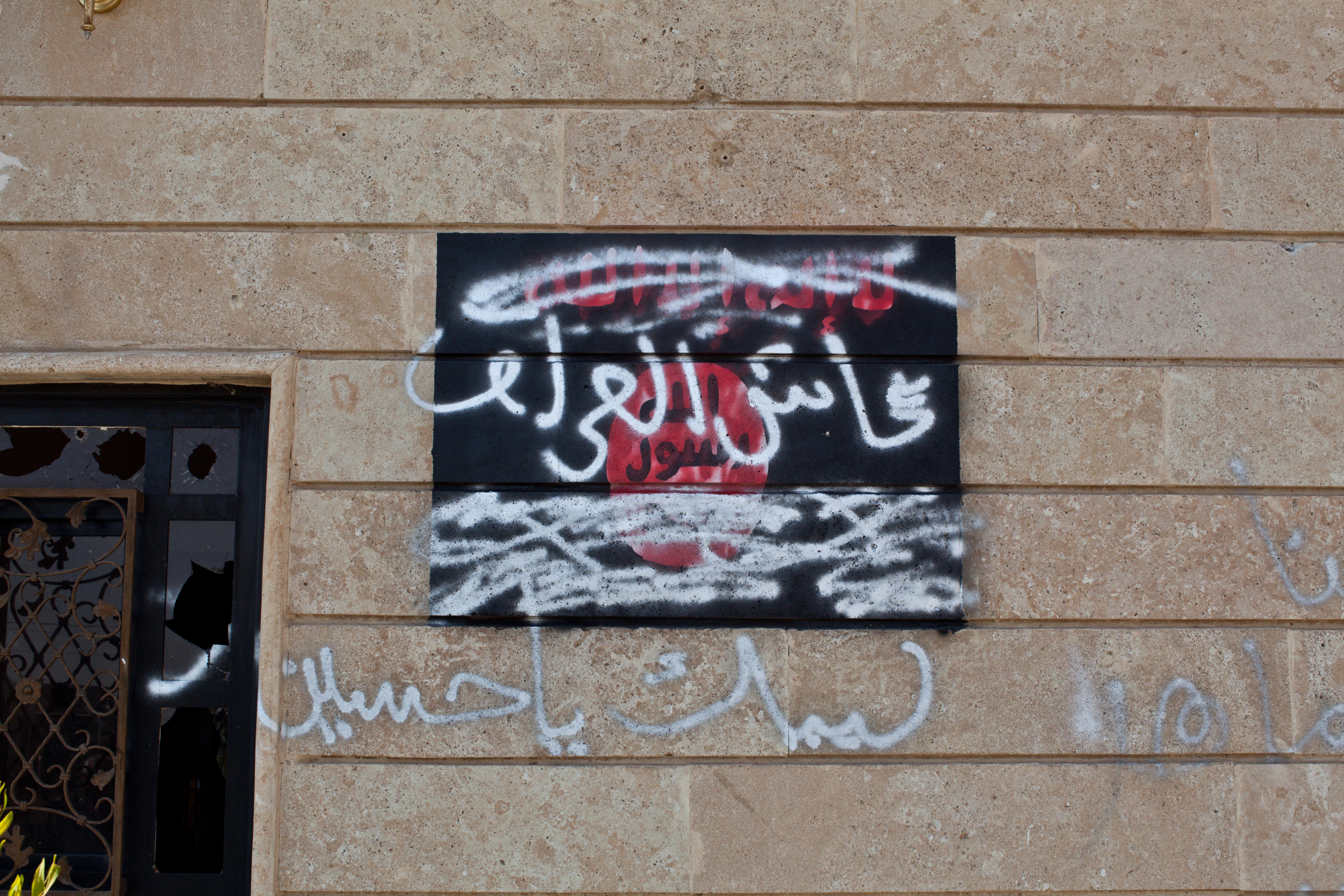 The ISIL flag on the outside of their islamic court is covered in pro-Iraqi graffiti. Image by Sebastian Meyer. Iraq, 2014. Media file: sebastian_meyer_amerli_11.jpg