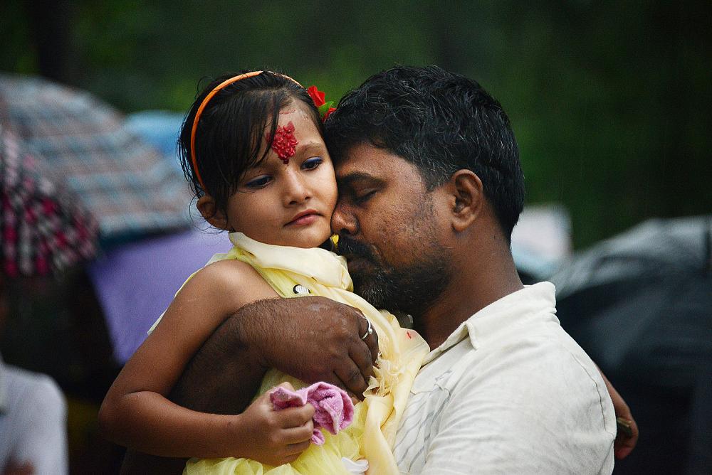 Smile Devan, 33, a Nepali citizen, says his final goodbyes to his daughter, Rina Shah, 7, before she, her brother and mother leave the refugee camp for the United States. Smile, who is not a refugee, does not know when he will see his two children again since he is not eligible to resettle. Image by Julia Rendleman. Nepal, 2014. Media file: 20140914jrnepalleavinglocal8-1.jpg