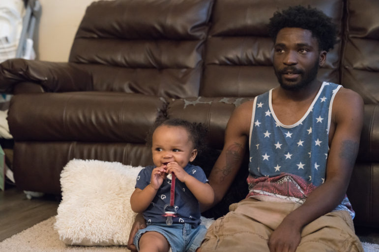 Theron Carson sits on the floor with his daughter watching cartoons. Carson was charged with trafficking marijuana and had $1,200 seized from his home after the police smelled weed coming from his Newburg apartment and conducted a search. Image by J. Tyler Franklin. United States, 2019. Theron Carson sits on the floor with his daughter watching cartoons. Carson was charged with trafficking marijuana and had $1,200 seized from his home after the police smelled weed coming from his Newburg apartment and conducted a search. Image by J. Tyler Franklin. United States, 2019.