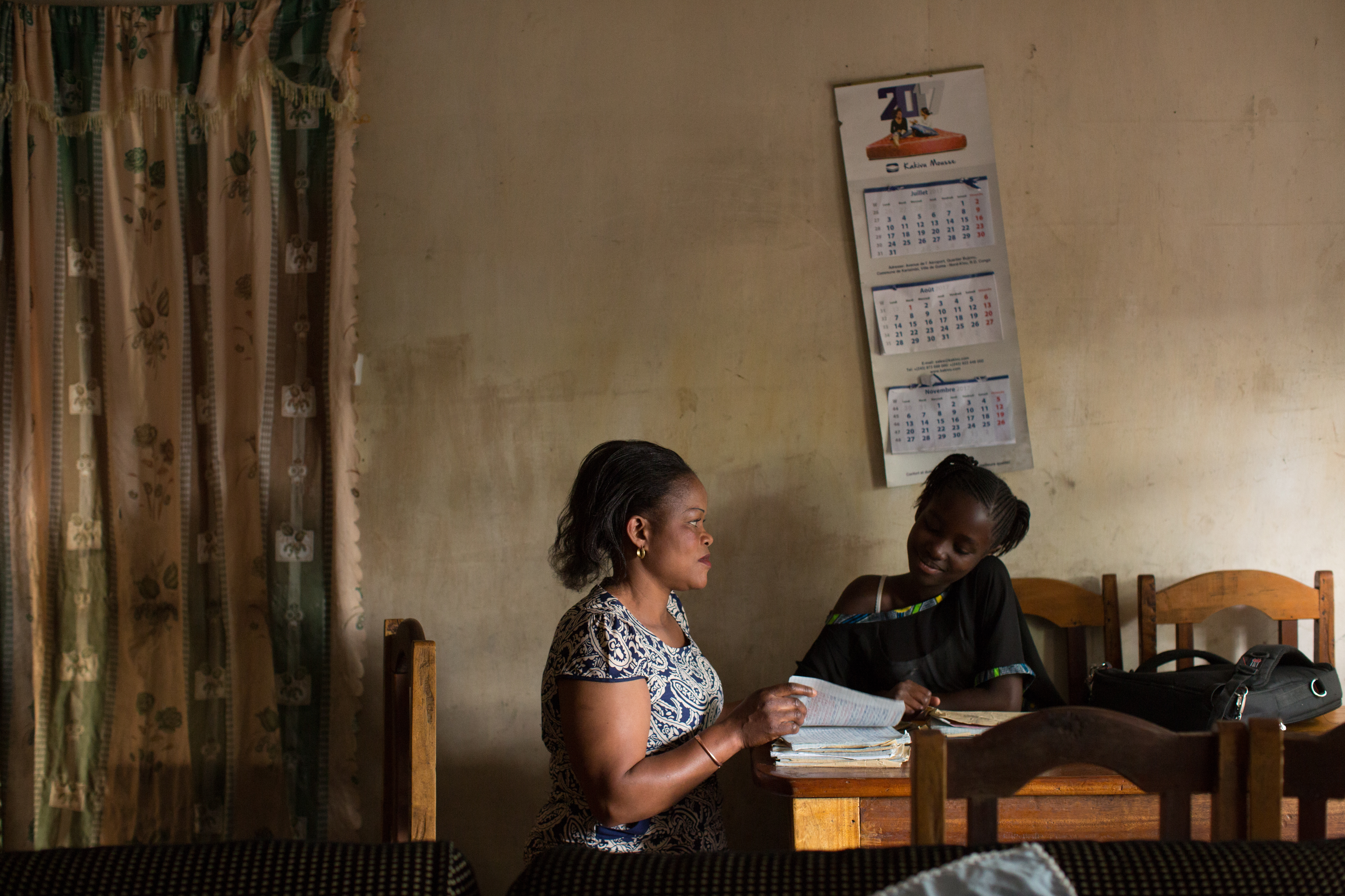FARDC captain Fanni Katora, 34, looks over the school work of her daughter Syntiche, 10, after work at their home in Goma, D.R. Congo, November 29, 2017. Image by Allison Shelley. Democratic Republic of Congo, 2017. FARDC captain Fanni Katora, 34, looks over the school work of her daughter Syntiche, 10, after work at their home in Goma, D.R. Congo, November 29, 2017. Image by Allison Shelley. Democratic Republic of Congo, 2017.