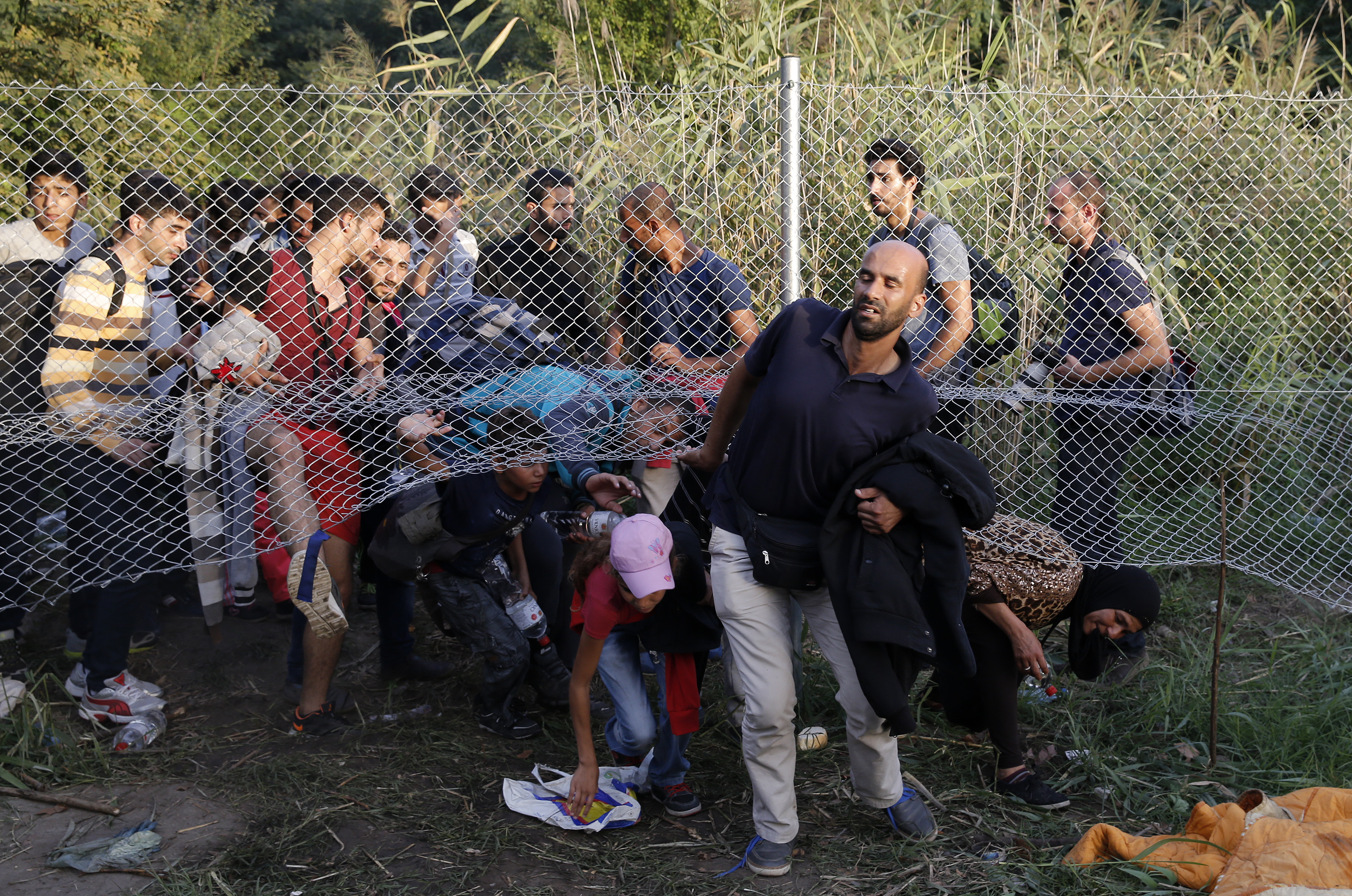 Migrants pass under a highway security fence as they try to find a new way to enter Hungary after Hungarian police sealed the border with Serbia near the village of Horgos, Serbia. Image courtesy of REUTERS/Marko Djurica. Hungary, 2015. Media file: refugees_hungary001.jpg