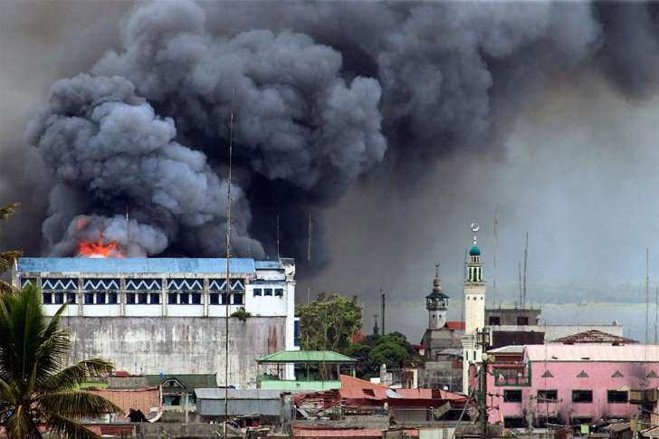 A building in Marawi is set ablaze by airstrikes carried out by the Philippine Air Force. Image by Mark Jhomel from Wikicommons. Philippines, 2017. (CC BY-SA 4.0) A building in Marawi is set ablaze by airstrikes carried out by the Philippine Air Force. Image by Mark Jhomel from Wikicommons. Philippines, 2017. (CC BY-SA 4.0)