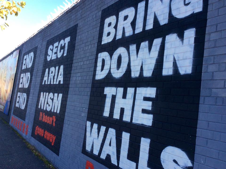 A mural reading 'End Sectarianism: Bring Down The Walls' on the Falls Road mural wall in Belfast. Image by Julia Canney. Northern Ireland, 2018 A mural reading 'End Sectarianism: Bring Down The Walls' on the Falls Road mural wall in Belfast. Image by Julia Canney. Northern Ireland, 2018.