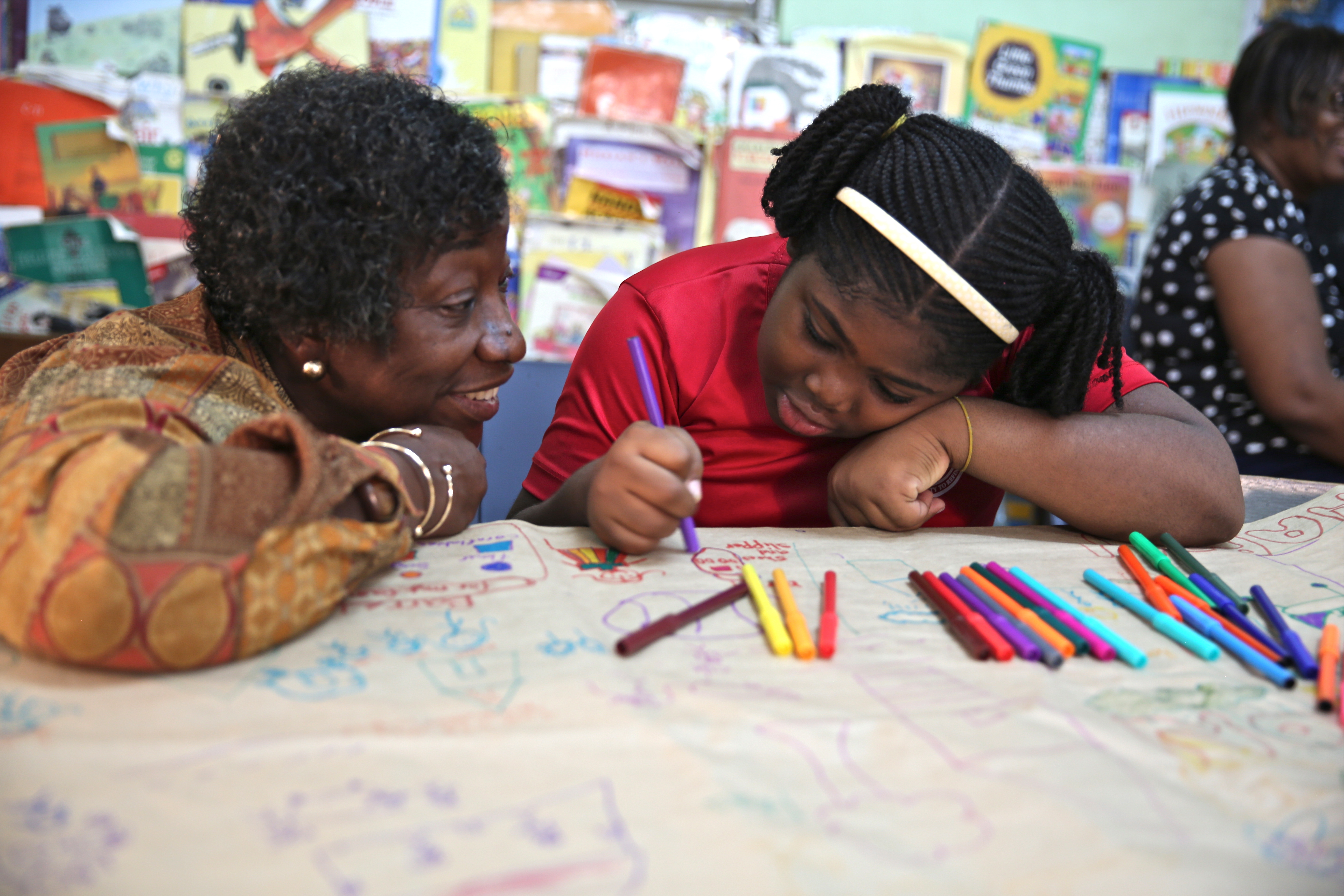 Dr. Claudette Crawford-Brown interacts with Shaniqua Long during an art therapy session at Shortwood Practising Infant, Primary and Junior High School in Kingston, Jamaica. Long's mother migrated to the United States. Image by Sabriya Simon. Jamaica. Dr. Claudette Crawford-Brown interacts with Shaniqua Long during an art therapy session at Shortwood Practising Infant, Primary and Junior High School in Kingston, Jamaica. Long's mother migrated to the United States. Image by Sabriya Simon. Jamaica.