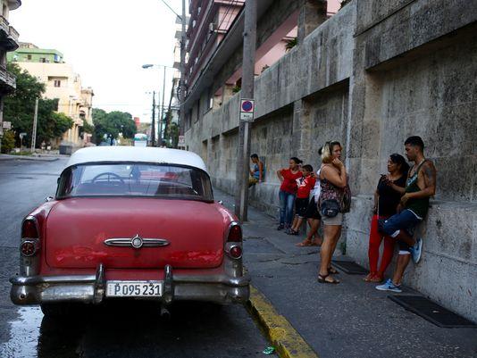 Musician Julio Cesar Onate, 27, far right, checks his email at a WiFi hotspot outside the Hotel Vedado in Havana. "There's a little more freedom in things we didn't have before," he said. "Now they give you the opportunity to get on the Internet." Image by Tracey Eaton. Cuba, 2015. Media file: 635726732155446731-julio2.jpg