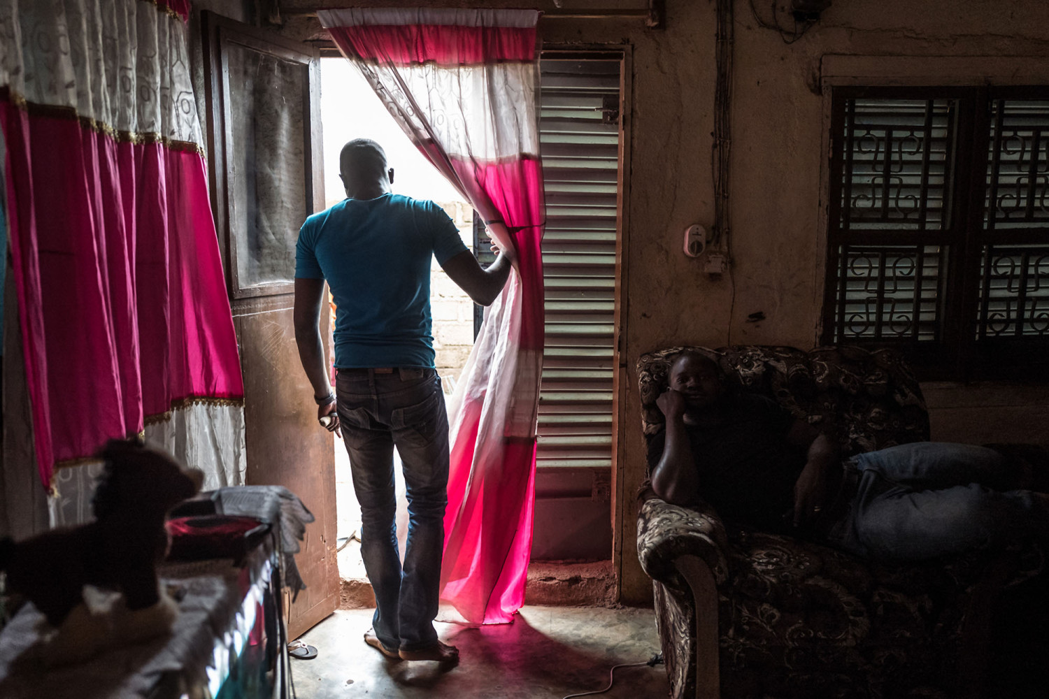 Abdoulaye Traoré stands in the doorway of his uncle’s house in Bamako. Traoré wasn’t sure he could afford to attend law school in the capital, but his uncle agreed to pay the $2.90 in monthly rent for a single room Traoré now shares with two other young men. Image by Nichole Sobecki. Mali, 2017. Abdoulaye Traoré stands in the doorway of his uncle’s house in Bamako. Traoré wasn’t sure he could afford to attend law school in the capital, but his uncle agreed to pay the $2.90 in monthly rent for a single room Traoré now shares with two other young men. Image by Nichole Sobecki. Mali, 2017.