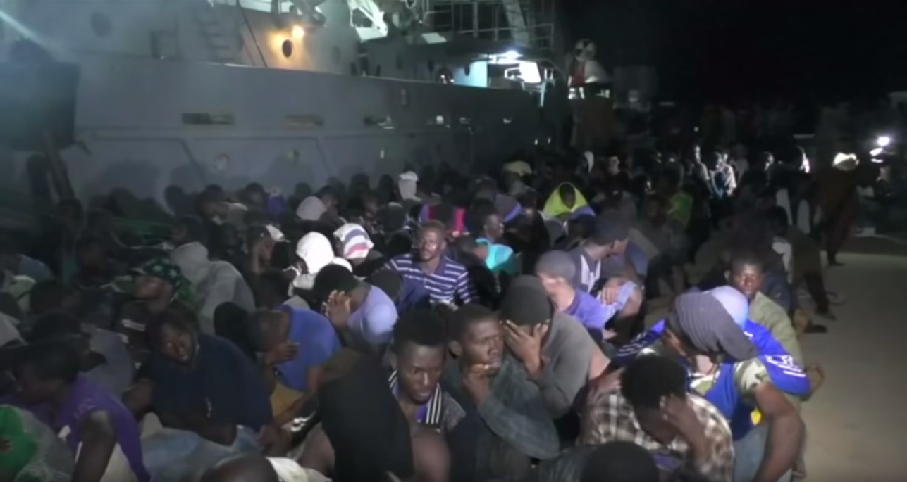 Migrants sit in a shipyard. Port city Sabratha used to be the migrant capital of Libya. Image courtesy of PBS NewsHour. Libya, 2018. Migrants sit in a shipyard. Port city Sabratha used to be the migrant capital of Libya. Image courtesy of PBS NewsHour. Libya, 2018.