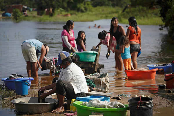 Women wash clothes along a flooded street on the outskirts of Trinidad, northeast of La Paz. Violence against women affects more than 50 percent of Bolivian women, but until this year it was rarely discussed by political candidates. Image by David Mercado. Bolivia, 2014. Media file: 100714-oboliviadomesticviolence_full_600.jpg