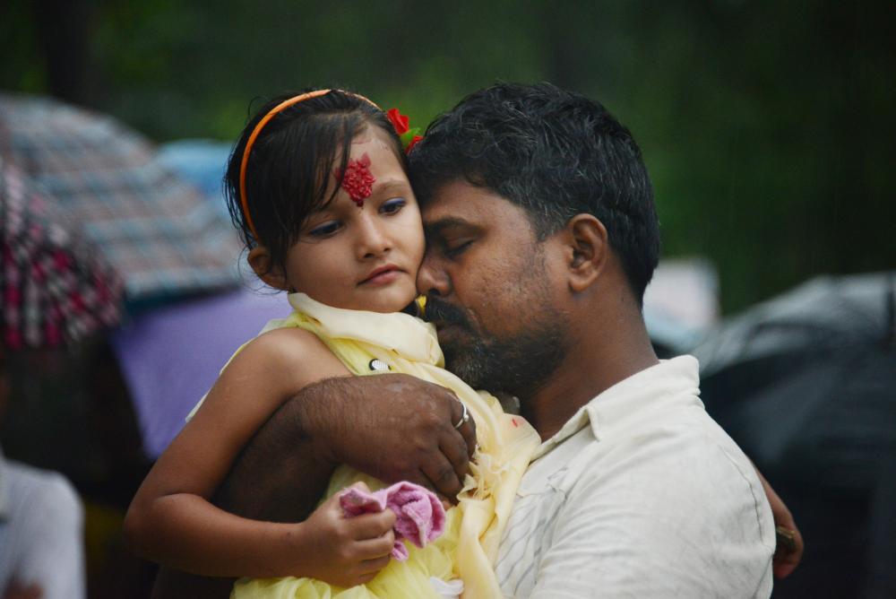 Smile Devan, 33, a Nepali citizen, says his final goodbyes to his daughter, Rina Shah, 7, before she, her brother and mother leave the refugee camp for the United States. Devan, who is not a refugee, does not know when he will see his two children again since he is not eligible to resettle. Image by Julia Rendleman. Nepal, 2014. Media file: leaving1.jpg
