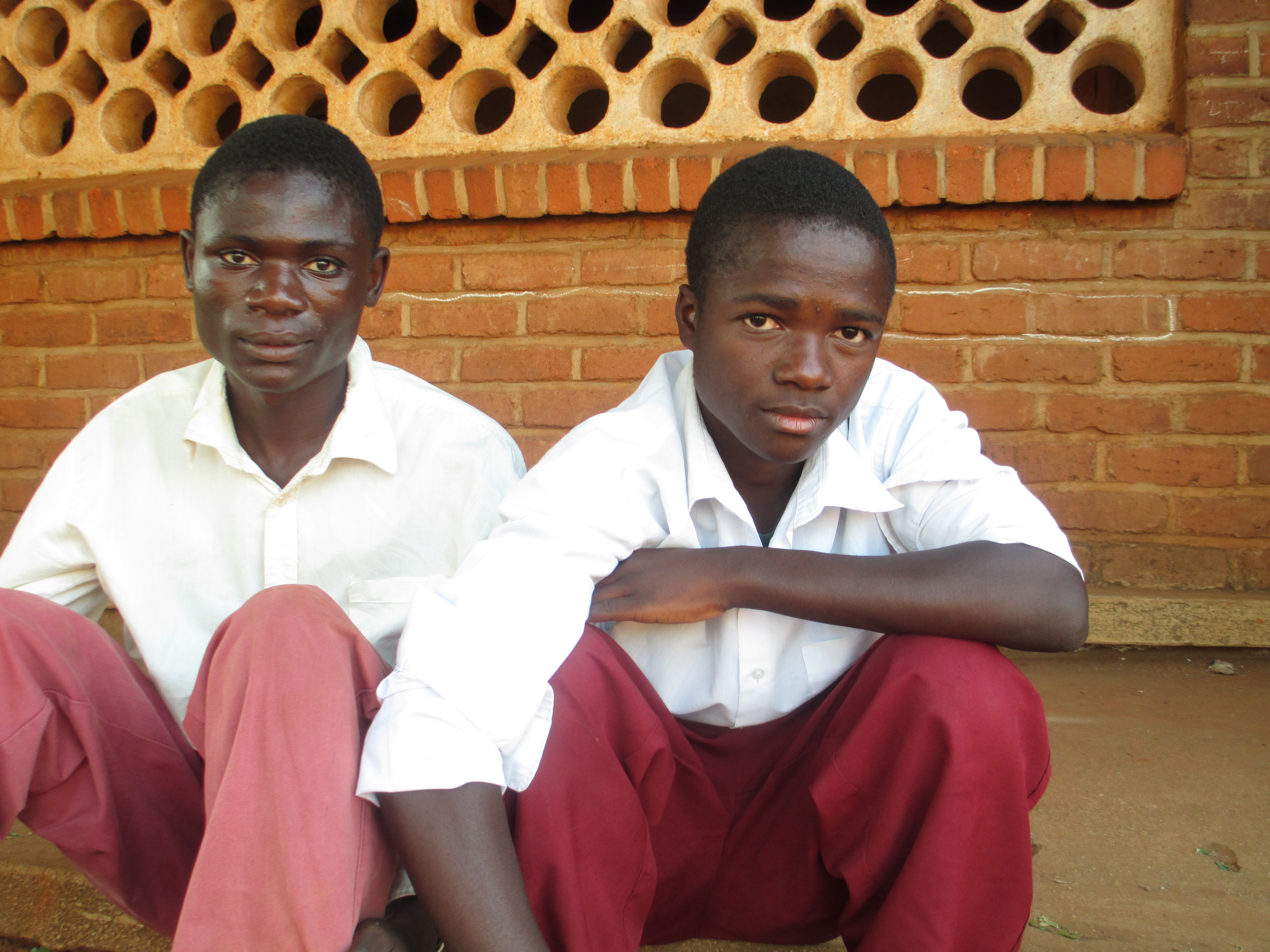 Two Malawian school boys who have been selected to receive cash transfers sit in front of their secondary school. Image by Kerstin Egenhofer. Malawi, 2013. Media file: img_0181.jpg