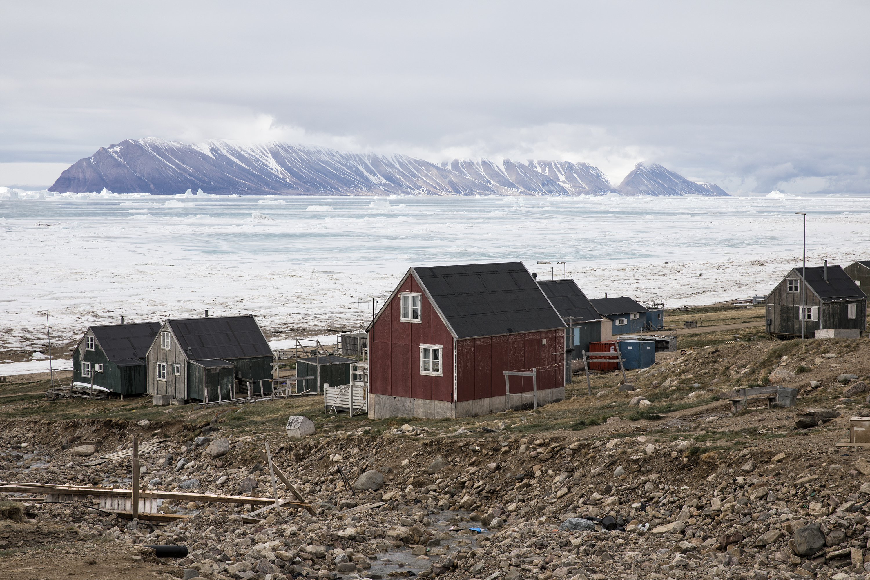 Many of the residents in Qaanaaq live in permafrost areas, and their homes are built on frozen ground. As the permafrost thaws, the ground becomes weaker and less able to support these structures, and it becomes dangerous to live inside. In parts of North Greenland, coastlines and soil are being eroded as storms batter the land and the permafrost crumbles. Image by Anna Filipova. Greenland, 2018. Many of the residents in Qaanaaq live in permafrost areas, and their homes are built on frozen ground. As the permafrost thaws, the ground becomes weaker and less able to support these structures, and it becomes dangerous to live inside. In parts of North Greenland, coastlines and soil are being eroded as storms batter the land and the permafrost crumbles. Image by Anna Filipova. Greenland, 2018.