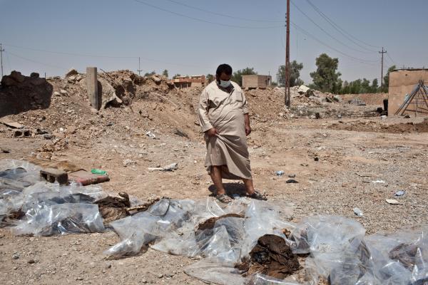 A local man inspects the exhumed bodies of five civilians who were killed by ISIL militants. Image by Sebastian Meyer. Iraq, 2014. Media file: sebastian_meyer_amerli_02.jpg