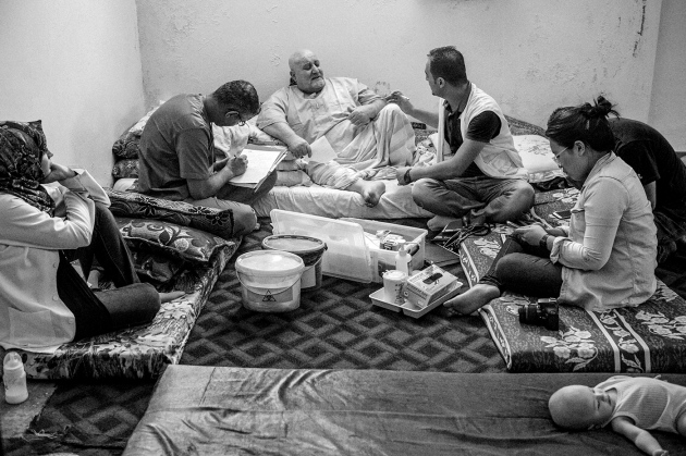 A doctor and technicians record health data on a Syrian refugee in Jordan. Image by Neil Brandvold. Jordan, 2017. A doctor and technicians record health data on a Syrian refugee in Jordan. Image by Neil Brandvold. Jordan, 2017.