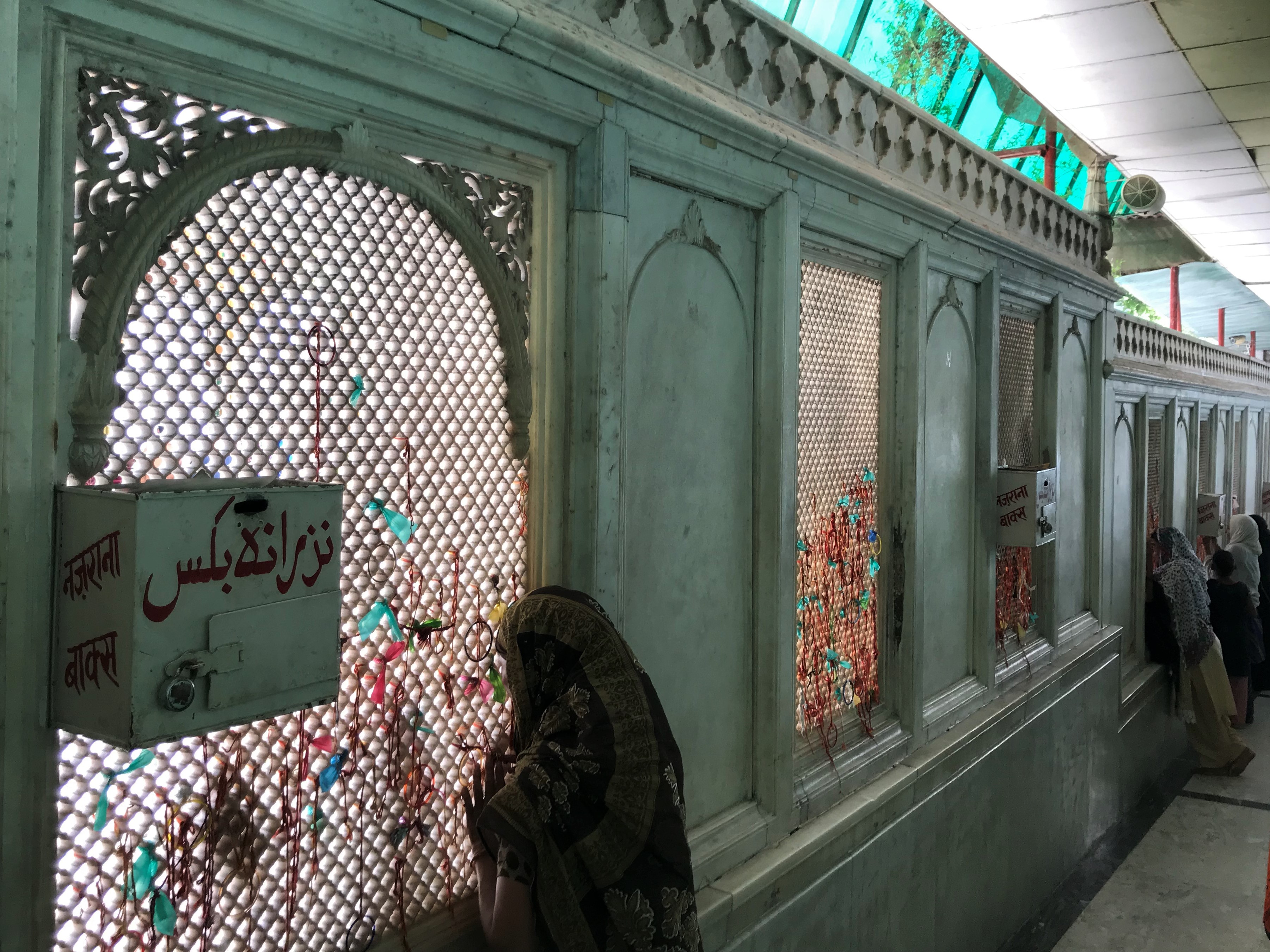 Women look through the jaali surrounding the courtyard of the dargah of Qutubuddin Bakhtiyar Kaki in Delhi. Image by Nikhil Mandalaparthy. India, 2019. Women look through the jaali surrounding the courtyard of the dargah of Qutubuddin Bakhtiyar Kaki in Delhi. Image by Nikhil Mandalaparthy. India, 2019.