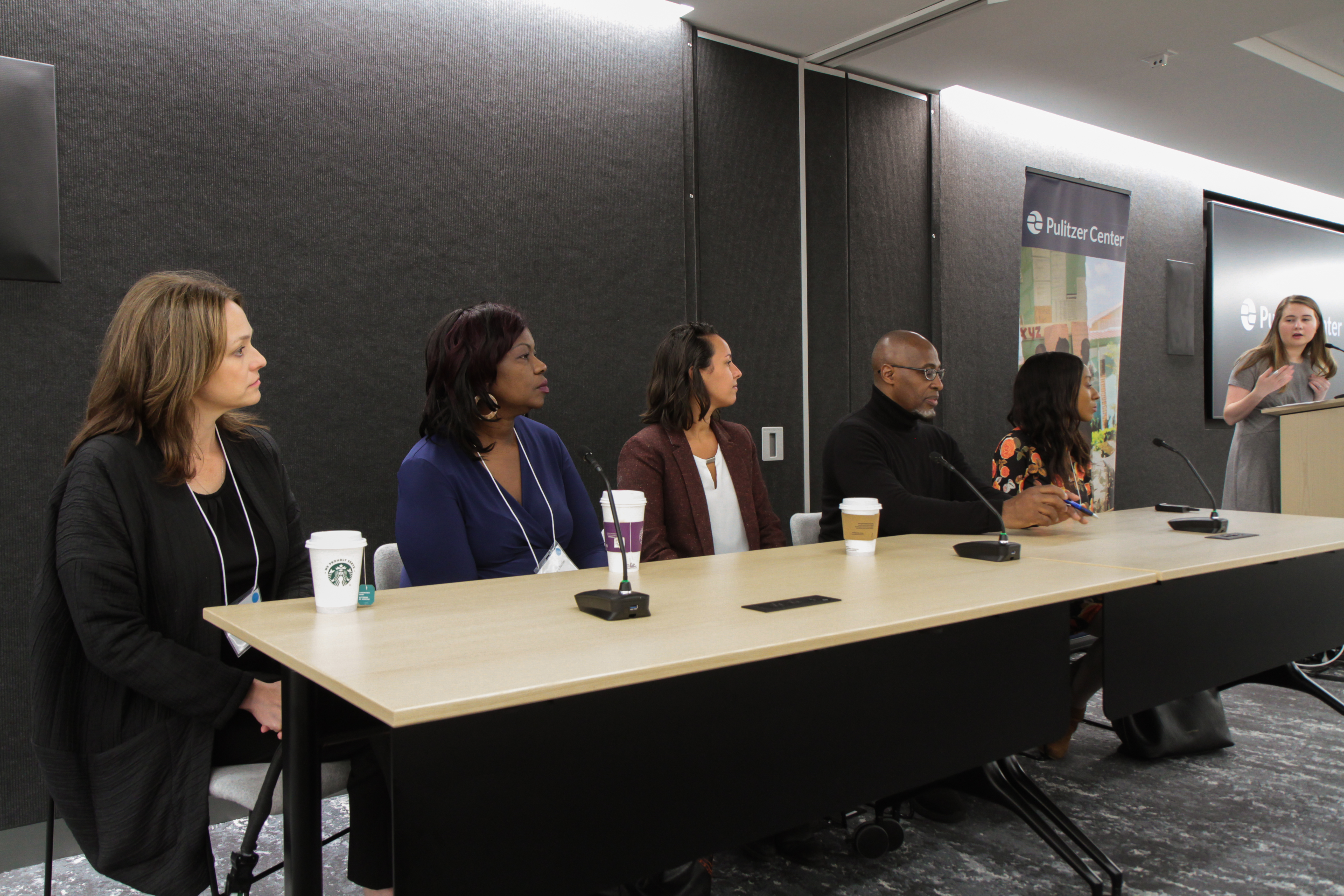 Pulitzer Center outreach coordinator Holly Piepenburg introduces the five panelists. From left to right: Time for Kids executive editor Jaime Joyce; Miami Herald correspondent Jacqueline Charles; digital video producer for National Geographic Gabrielle Ewing; senior investigative reporter for WGBH Phillip Martin; and multimedia reporter Melissa Noel. Image by Libby Moeller. United States, 2019. Pulitzer Center outreach coordinator Holly Piepenburg introduces the five panelists. From left to right: Time for Kids executive editor Jaime Joyce; Miami Herald correspondent Jacqueline Charles; digital video producer for National Geographic Gabrielle Ewing; senior investigative reporter for WGBH Phillip Martin; and multimedia reporter Melissa Noel. Image by Libby Moeller. United States, 2019.