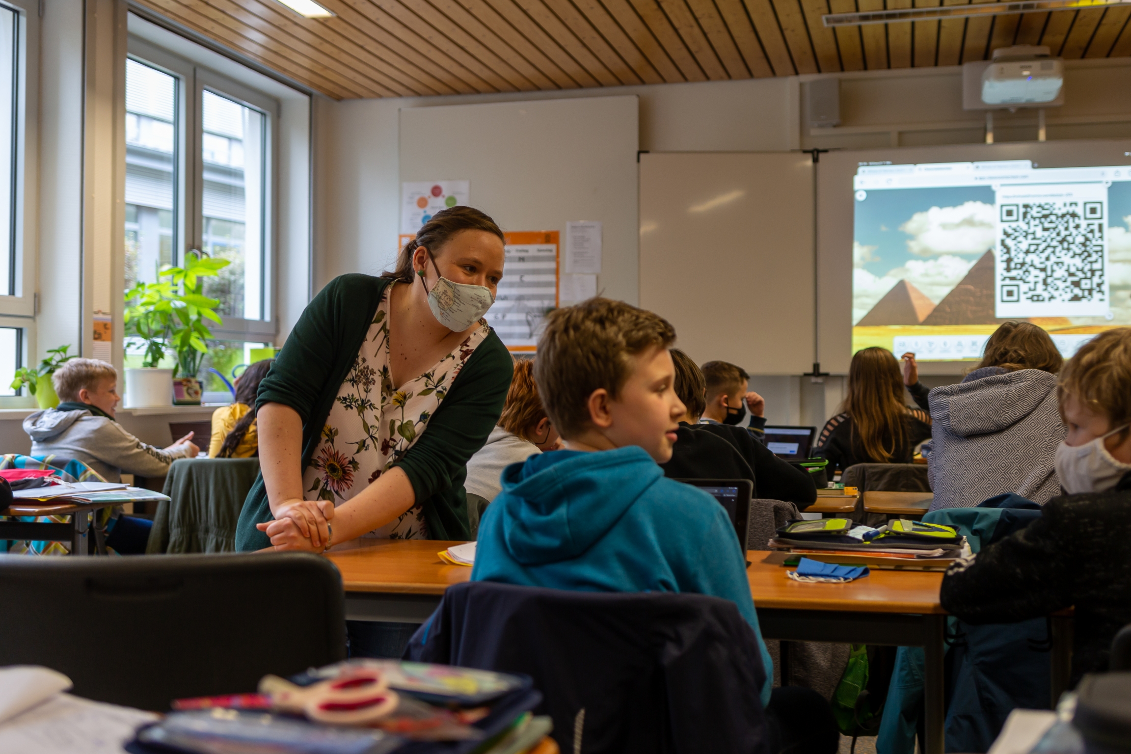 Teacher Inga Deppa works with students in an English class at Jacobishule in Kalletal, Germany. Masks were optional for students when they were seated at their desks, but the regional health authority has since tightened mask rules for older students. Image by Ryan Delaney. Germany, 2020. Teacher Inga Deppa works with students in an English class at Jacobishule in Kalletal, Germany. Masks were optional for students when they were seated at their desks, but the regional health authority has since tightened mask rules for older students. Image by Ryan Delaney. Germany, 2020.