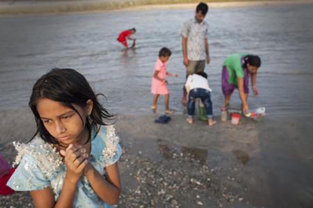 A girl worships with her family on a small river in the town of Jhapa, Nepal. Image by Steve Matzker. Nepal, 2013.