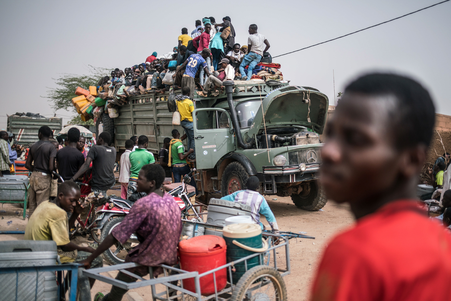 Young men crowd onto the back of an old Mercedes-Benz truck leaving Agadez for the far north of Niger where thousands are prospecting for gold in precarious conditions. Image by Nichole Sobecki. Niger, 2017. Young men crowd onto the back of an old Mercedes-Benz truck leaving Agadez for the far north of Niger where thousands are prospecting for gold in precarious conditions. Image by Nichole Sobecki. Niger, 2017.