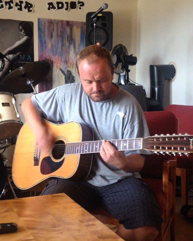 An inmate relaxes with his guitar in the living room—which doubles as a rehearsal room—in the blues band members' house on Bastøy Prison Island. Image by Britton Nagy. Norway, 2014. Media file: img_4602.jpg