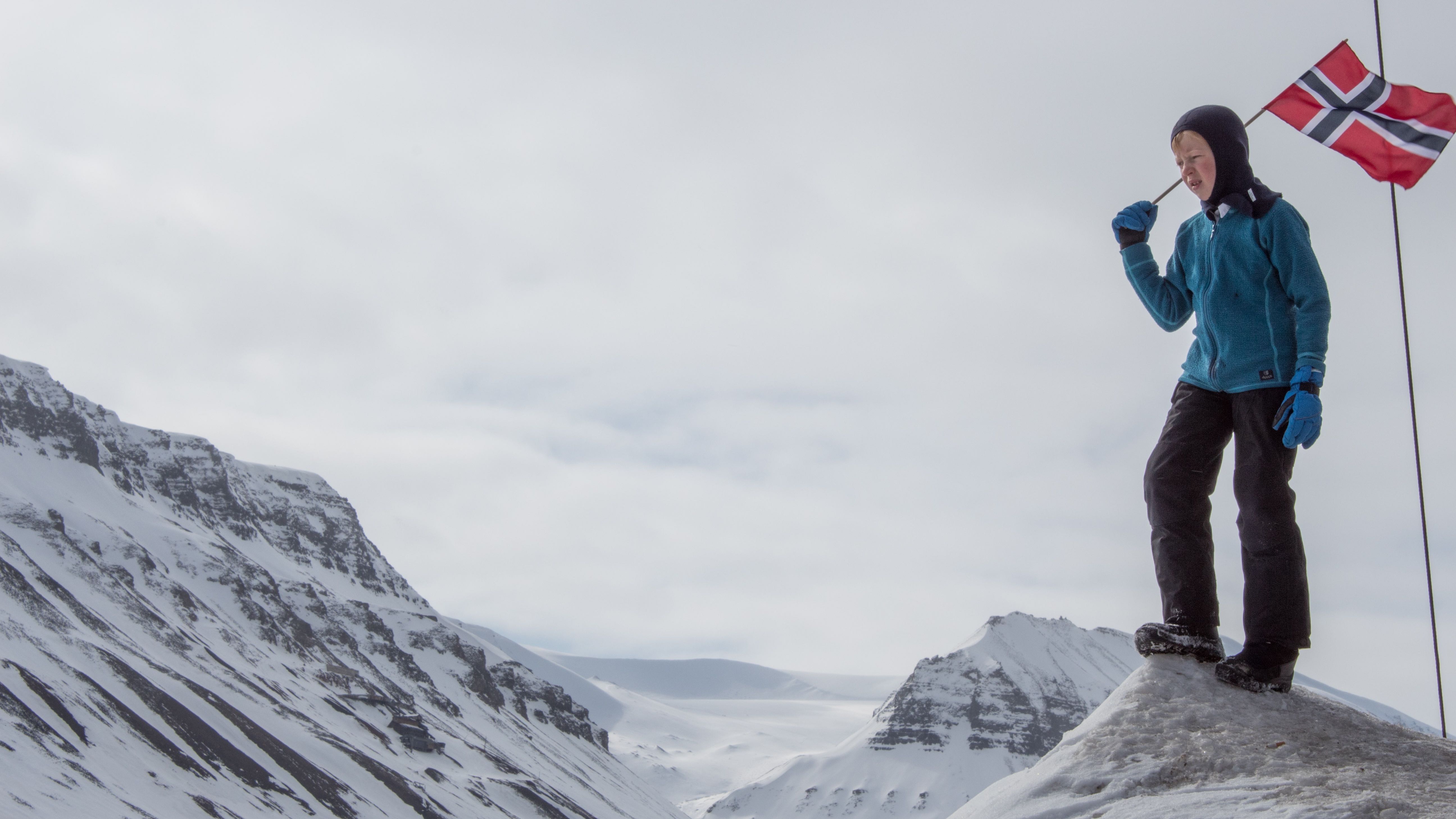 A child carries a Norwegian flag on a high Arctic landscape. Image by Amy Martin. Norway, 2018. A child carries a Norwegian flag on a high Arctic landscape. Image by Amy Martin. Norway, 2018.