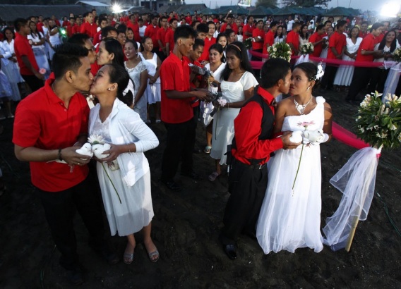 Newly wed couples kiss during a February mass wedding ceremony at Rosario town in Cavite City, south of Manila. Image by Romeo Ranoco. Philippines, 2014.