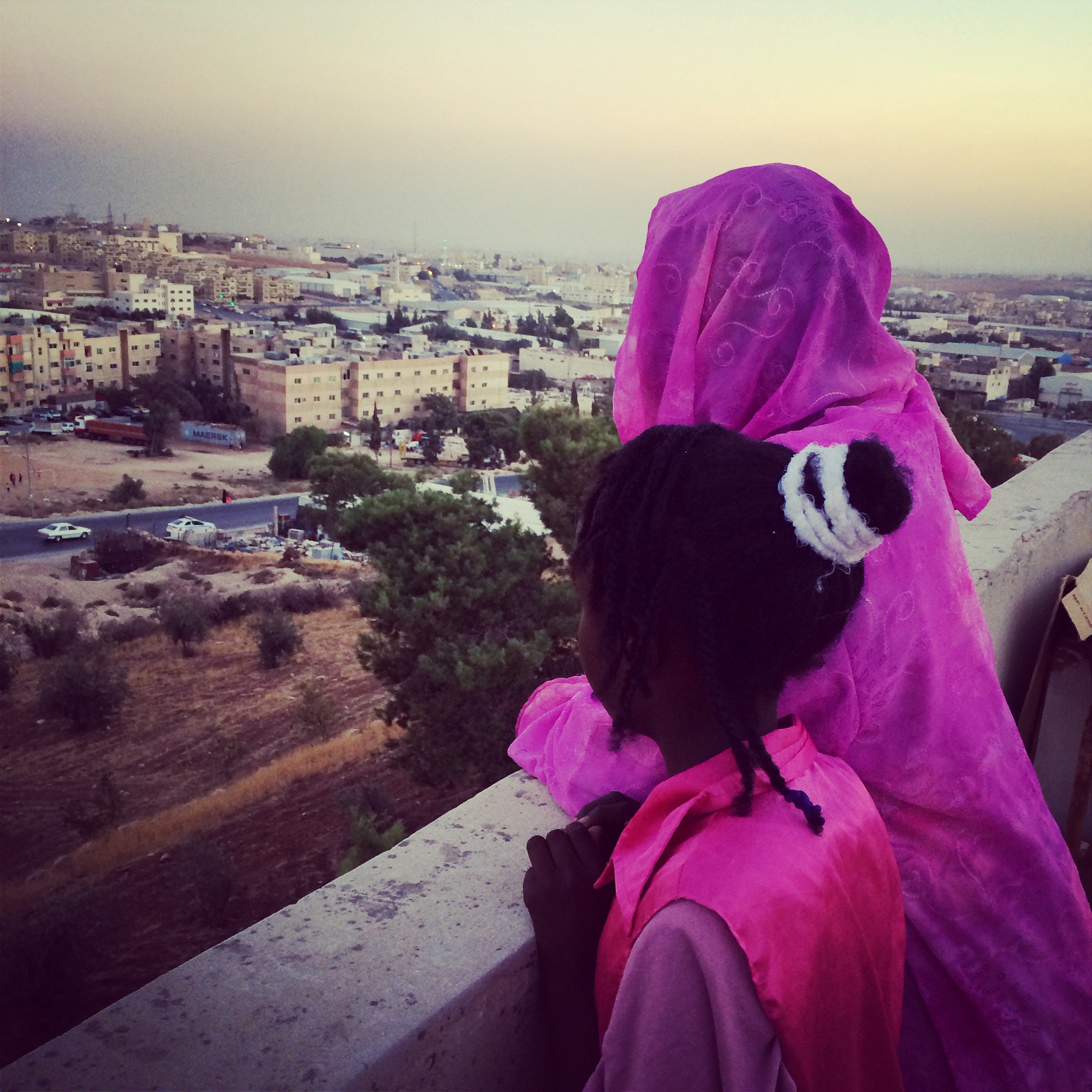 Sudanese refugees look over a balcony on the outskirts of Amman, Jordan. Image by Alice Su. Jordan, 2015.