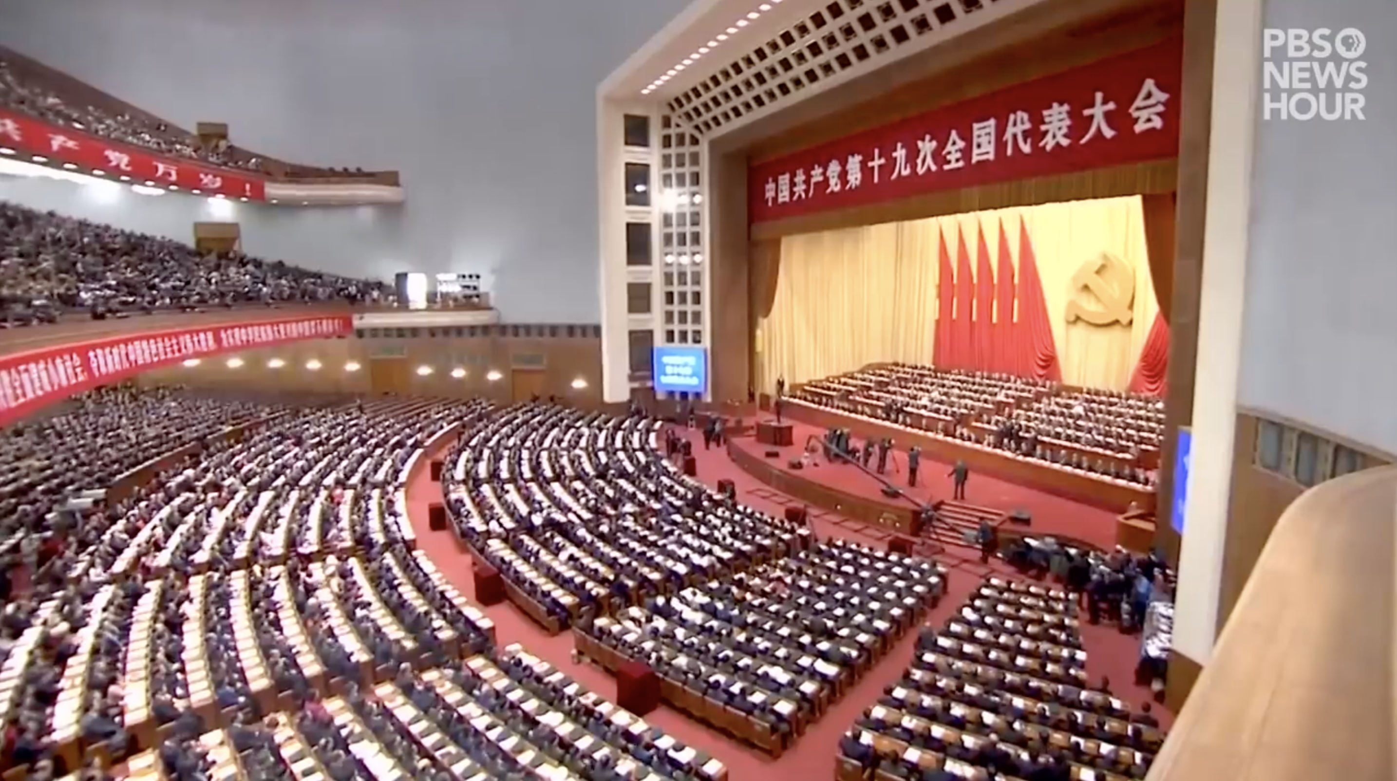 Image courtesy of PBS NewsHour. China, 2019. Image of auditorium and stage in China.