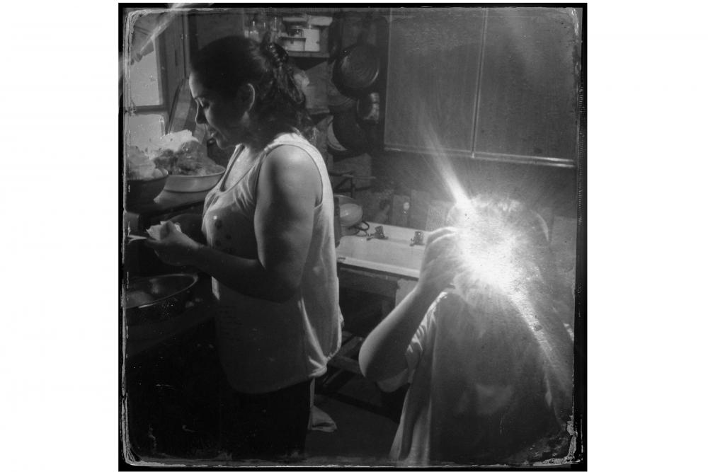 Pamela Betancur and her son Juan Jose Larraguibel in the kitchen of their house in a campamento, or shantytown, in the La Florida neighborhood in Santiago. Betancur came from from Los Angeles, in Southern Chile, to Santiago as a teenager. She said that she was planning to vote for Michelle Bachelet in the presidential election because Bachelet had created programs for women during her first term in office, from 2006 to 2010. Image by Jon Lowenstein. Chile, 2013. Media file: lowenstein1.jpg