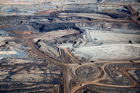 Giant dump trucks carry 400-ton loads of ore are dwarfed by the huge scale of a tar sands mine in Alberta. Image by Alex MacLean. Canada, 2014. Media file: untitled.jpg