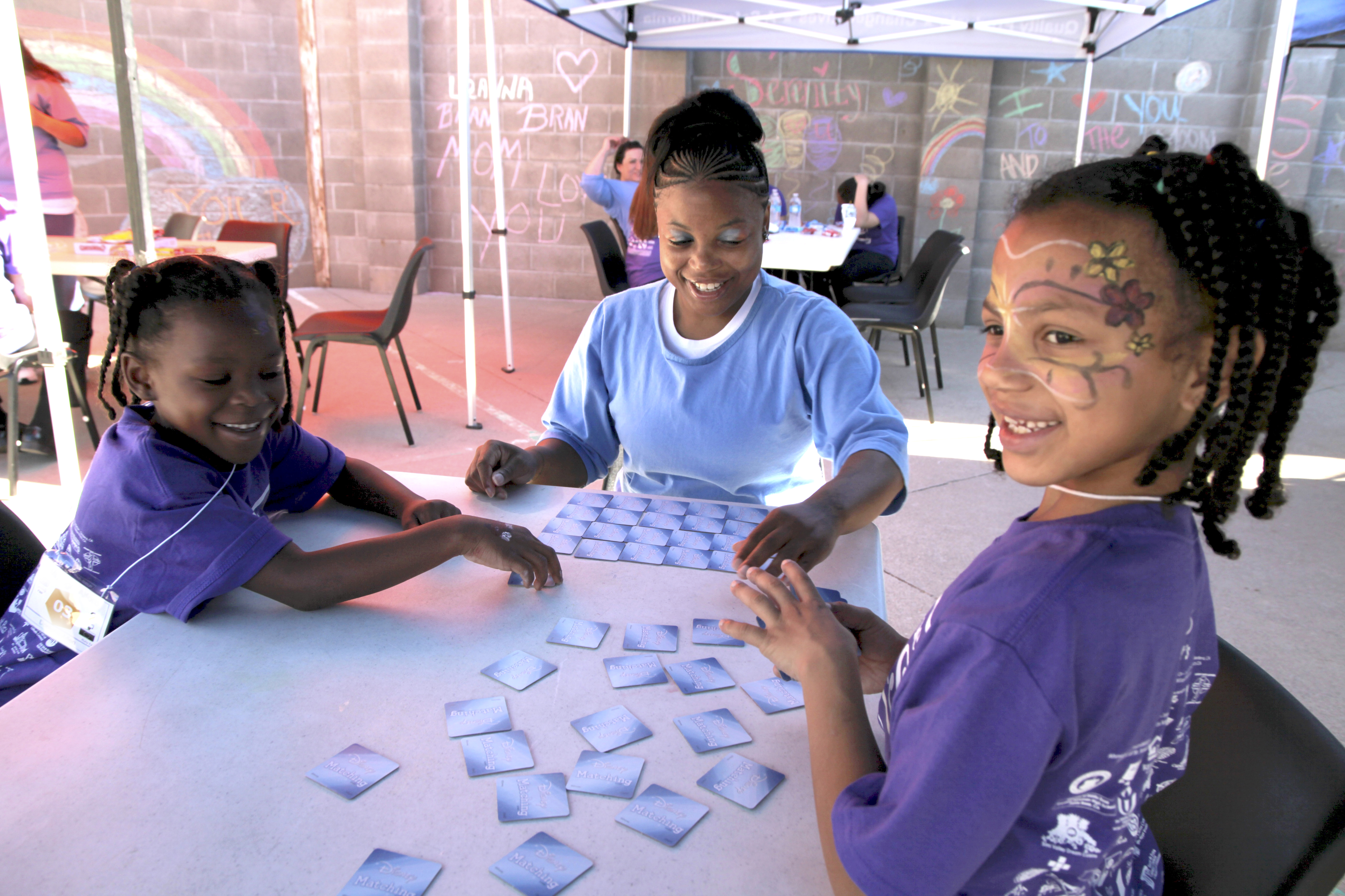 ALL SMILES Mi'Angel (left) and Mayal enjoy a card game with their mom, Donisha. Image by Jaime Joyce. United States, 2018. ALL SMILES Mi'Angel (left) and Mayal enjoy a card game with their mom, Donisha. Image by Jaime Joyce. United States, 2018.