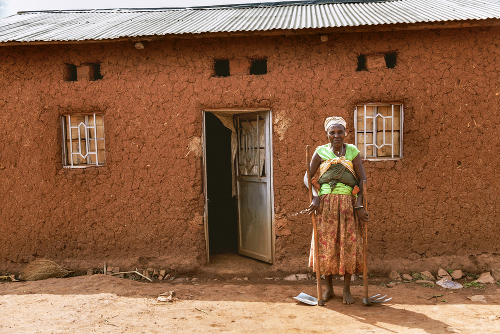 A Rwandan woman stands in front of her home. Image by sifkigali/Shutterstock. Rwanda, 2015. A Rwandan woman stands in front of her home. Image by sifkigali/Shutterstock. Rwanda, 2015.